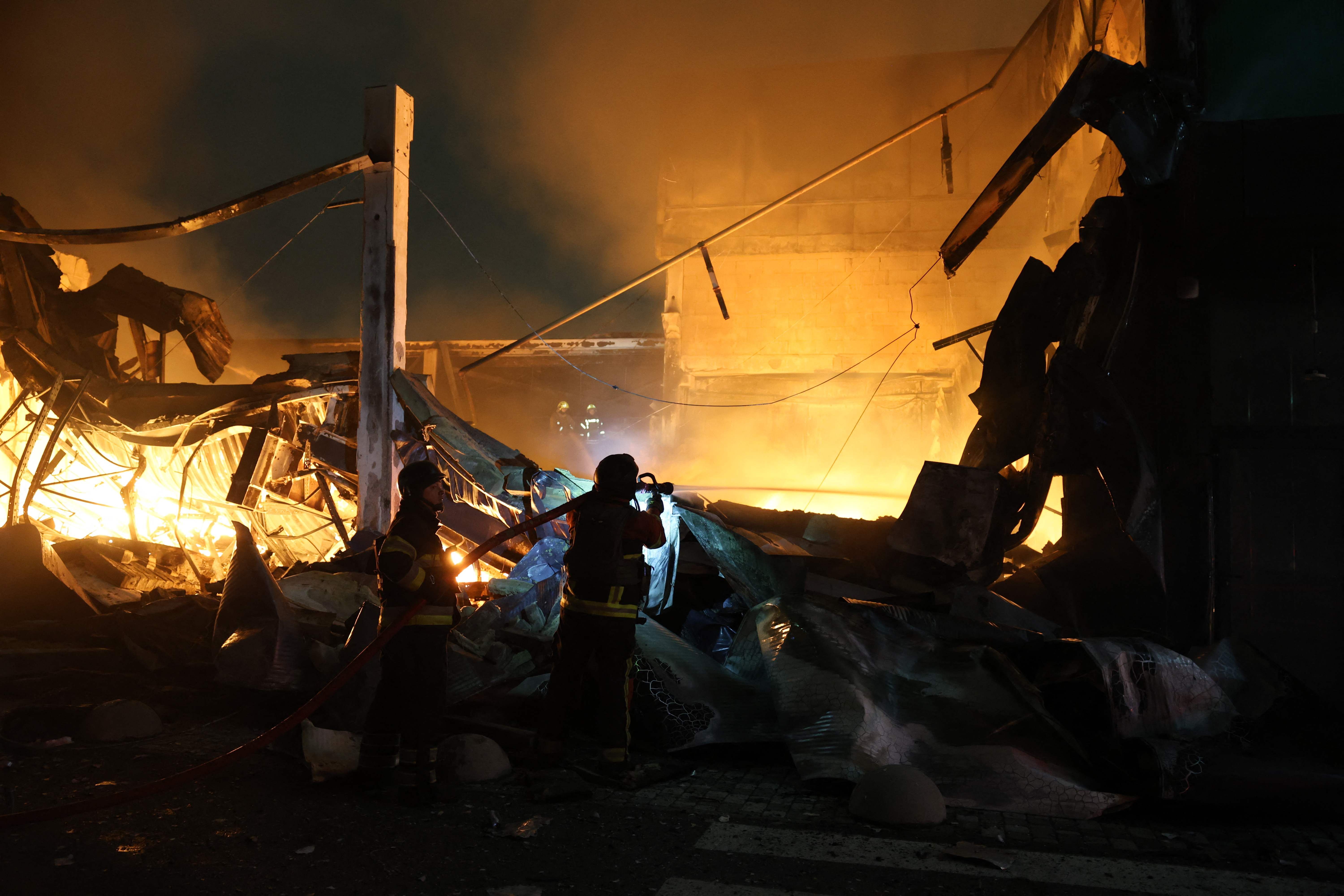 Feuerwehrleute löschen nachts ein brennendes, zerstörtes Einkaufszentrum in Kyiv.