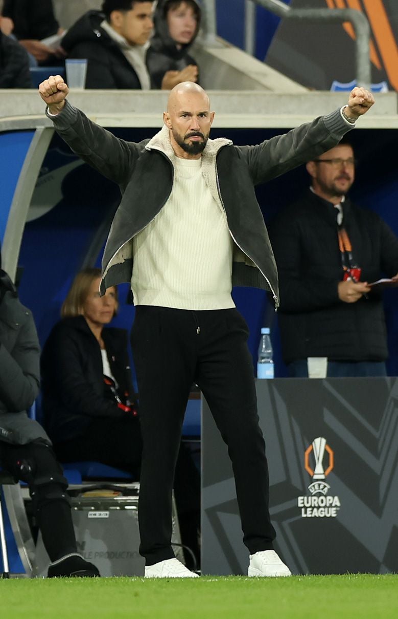 Ein Mann jubelt mit erhobenen Armen am Spielfeldrand während eines Fußballspiels.