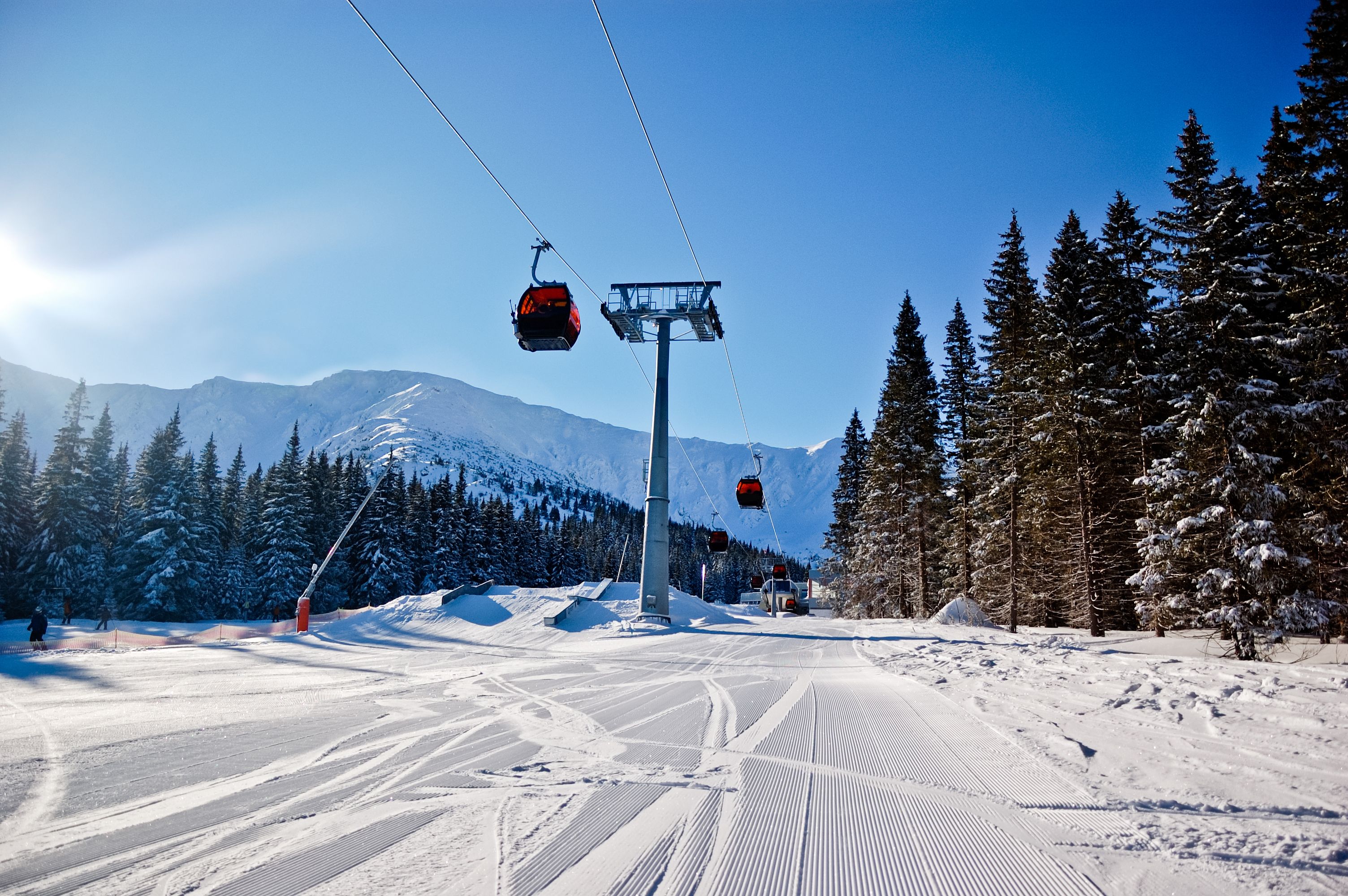 Frisch präparierte Skipiste mit Seilbahn und verschneiten Bäumen im Jasna Skigebiet, Slowakei.