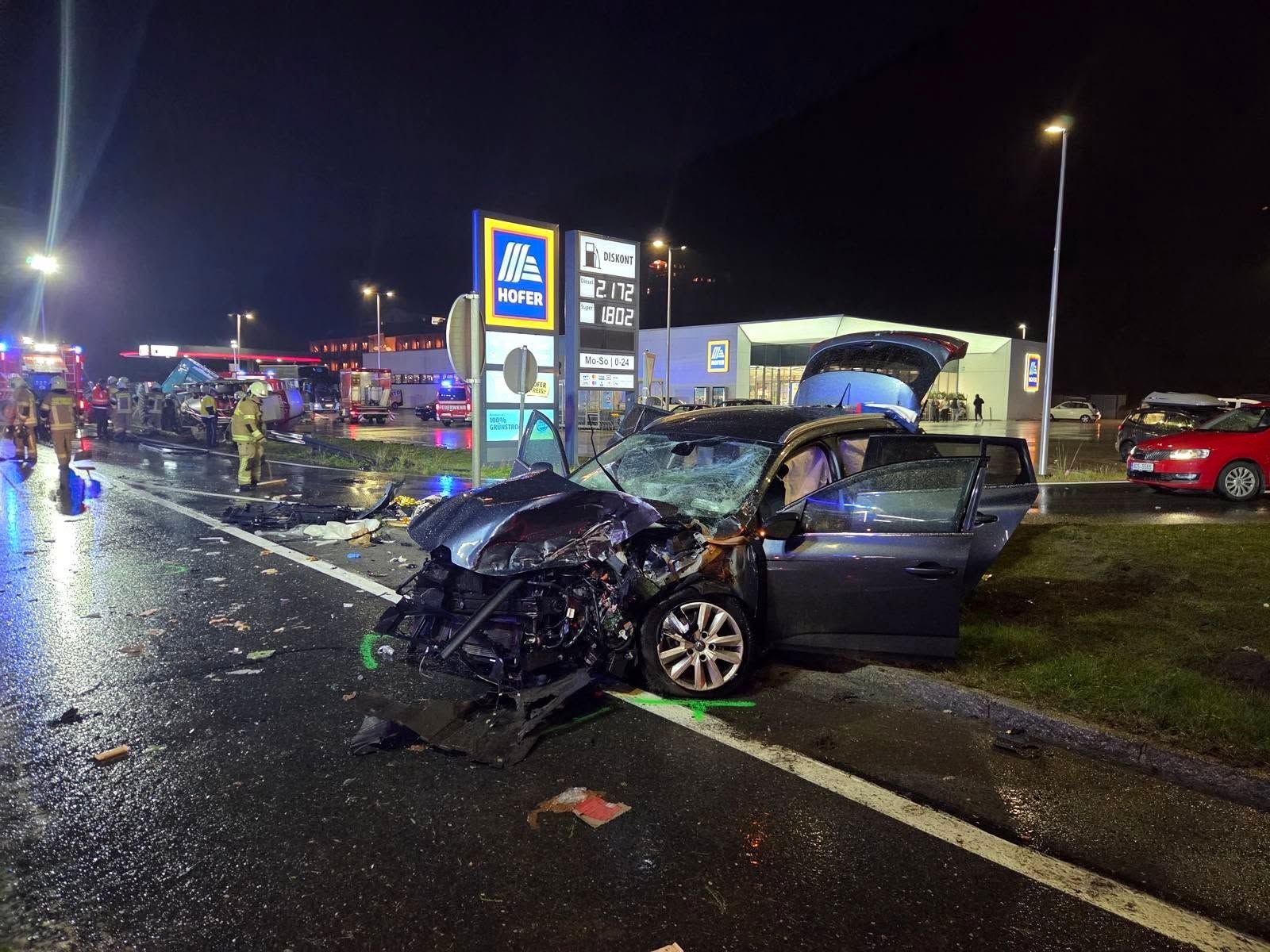 Schwerer Autounfall bei Nacht vor einem Hofer-Markt in Schladming, Einsatzkräfte vor Ort.