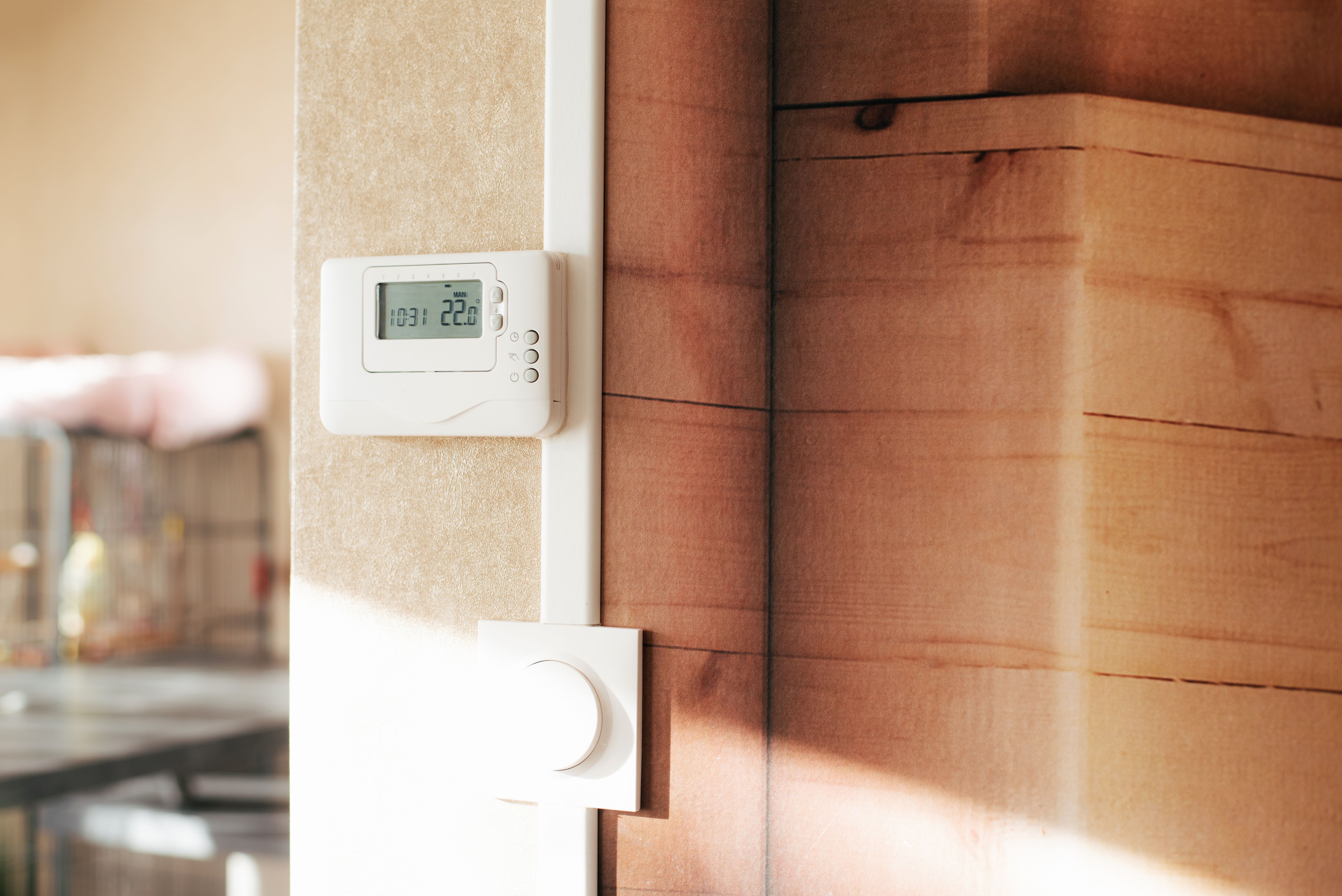 Ein Thermostat an einer Wand zeigt 22,0 °C an, darunter ein runder Drehregler.