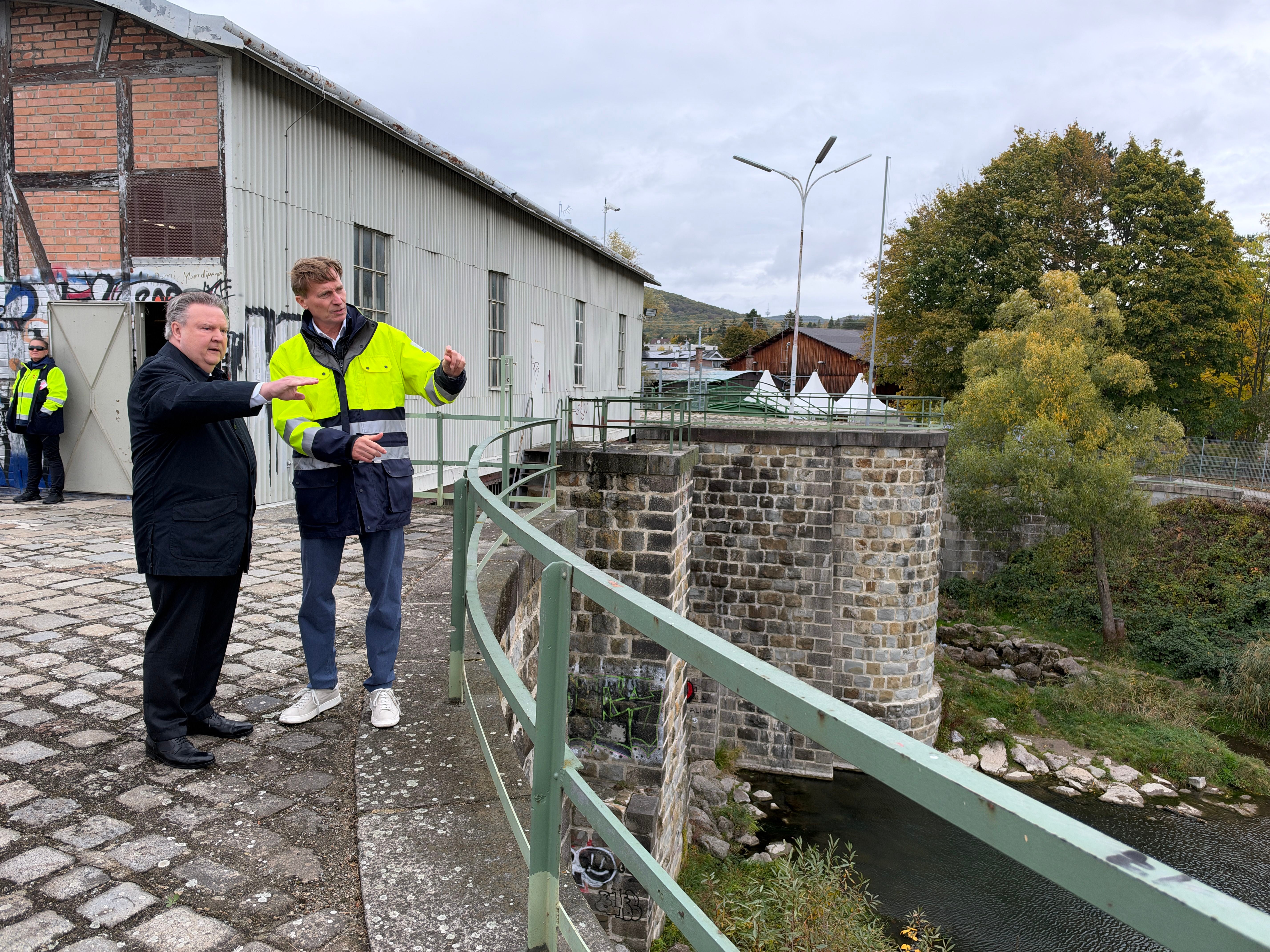 Zwei Männer besichtigen eine Hochwasserschutzanlage an einem Fluss.