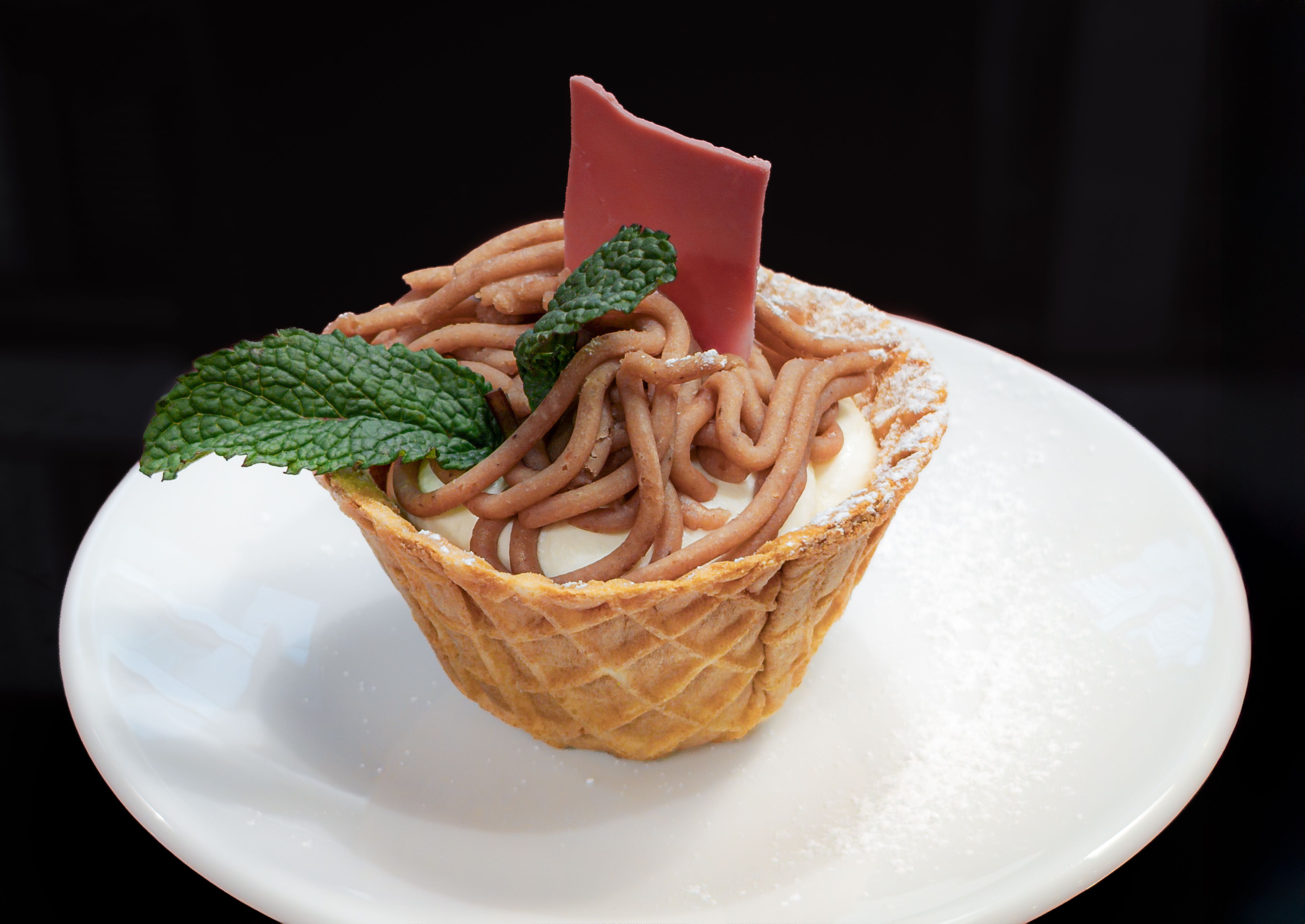 Schweizer Vermicelle-Dessert mit Kastanienpüree, Sahne, Minze und rosa Schokolade im Waffelbecher.