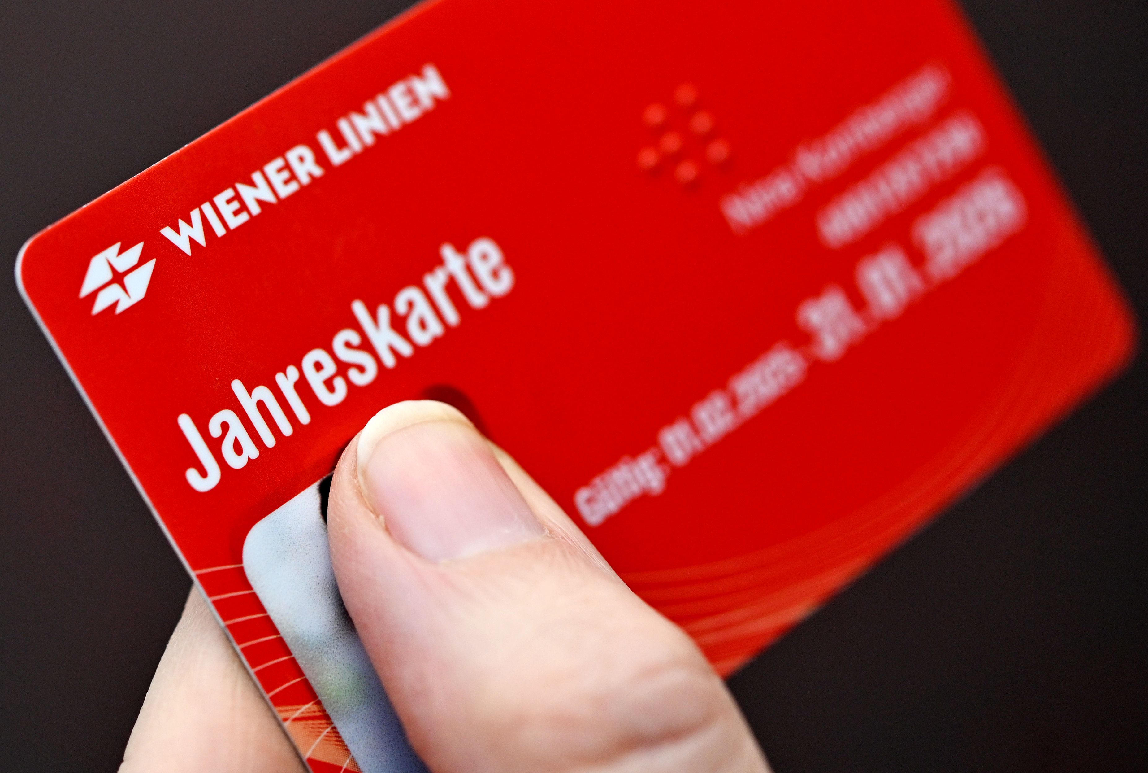 Eine Hand hält eine rote Jahreskarte der Wiener Linien für öffentliche Verkehrsmittel.