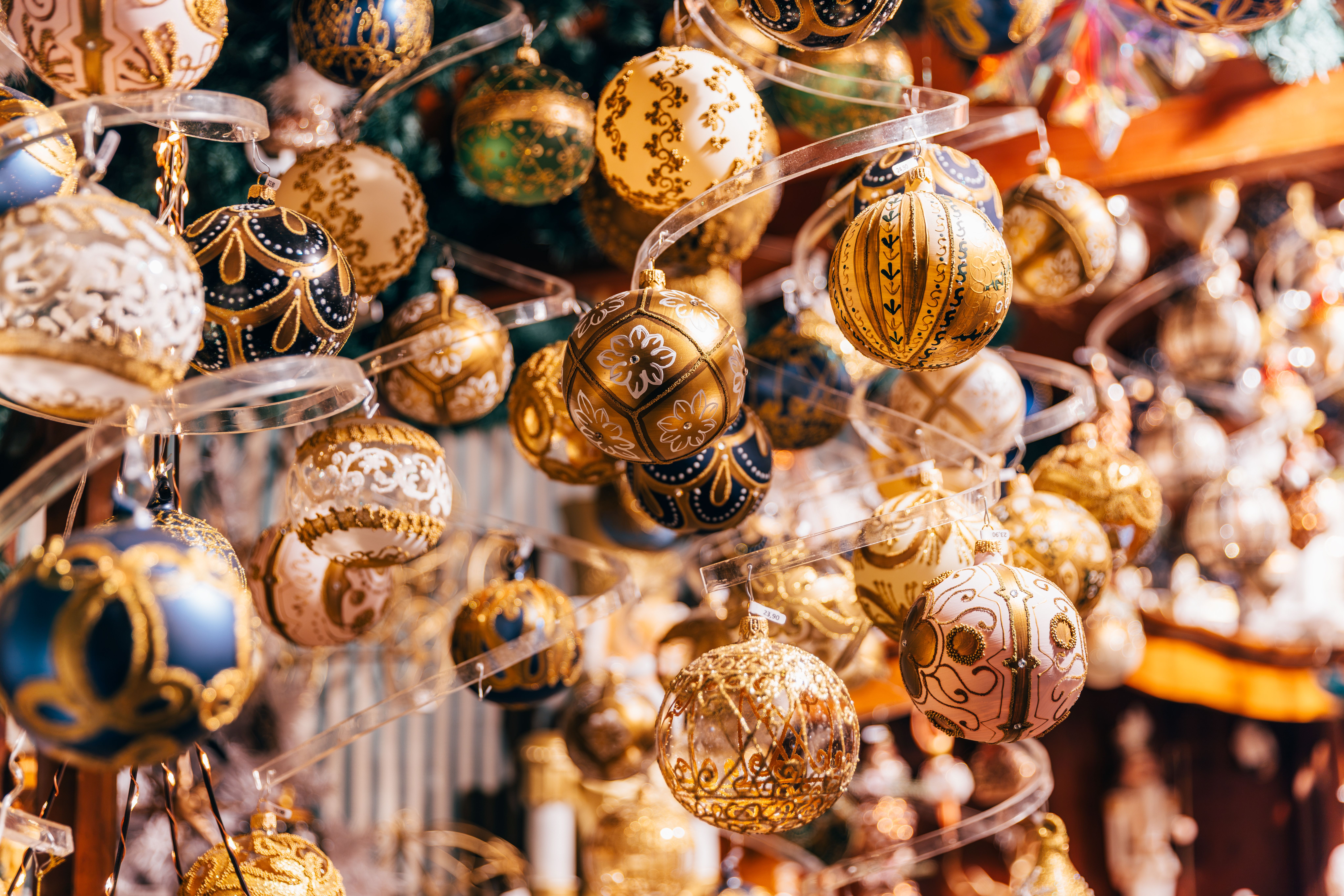 Viele bunt verzierte Christbaumkugeln hängen dicht nebeneinander an einem Verkaufsstand.