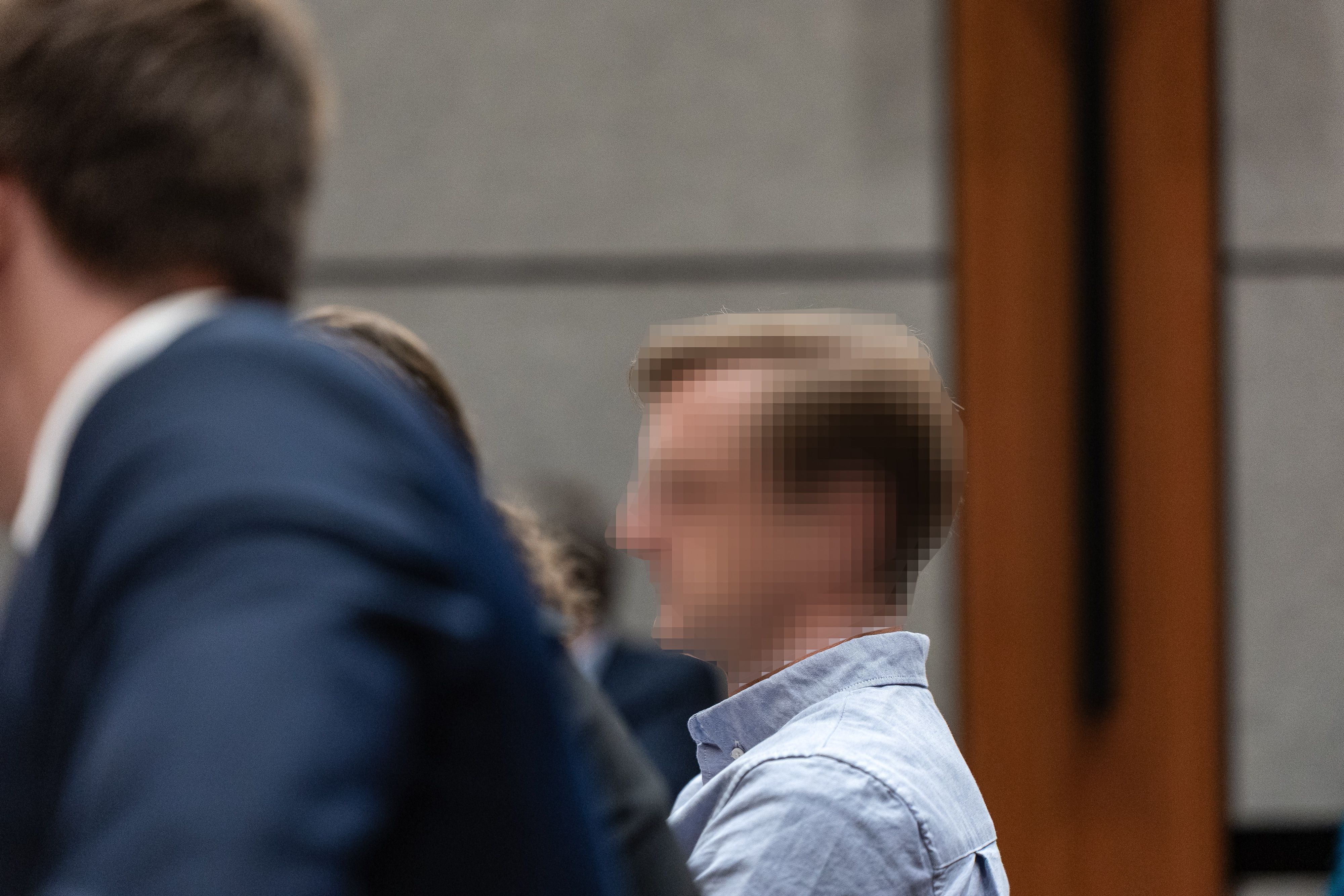 Ein Mann mit verpixeltem Gesicht sitzt in einem Gerichtssaal.