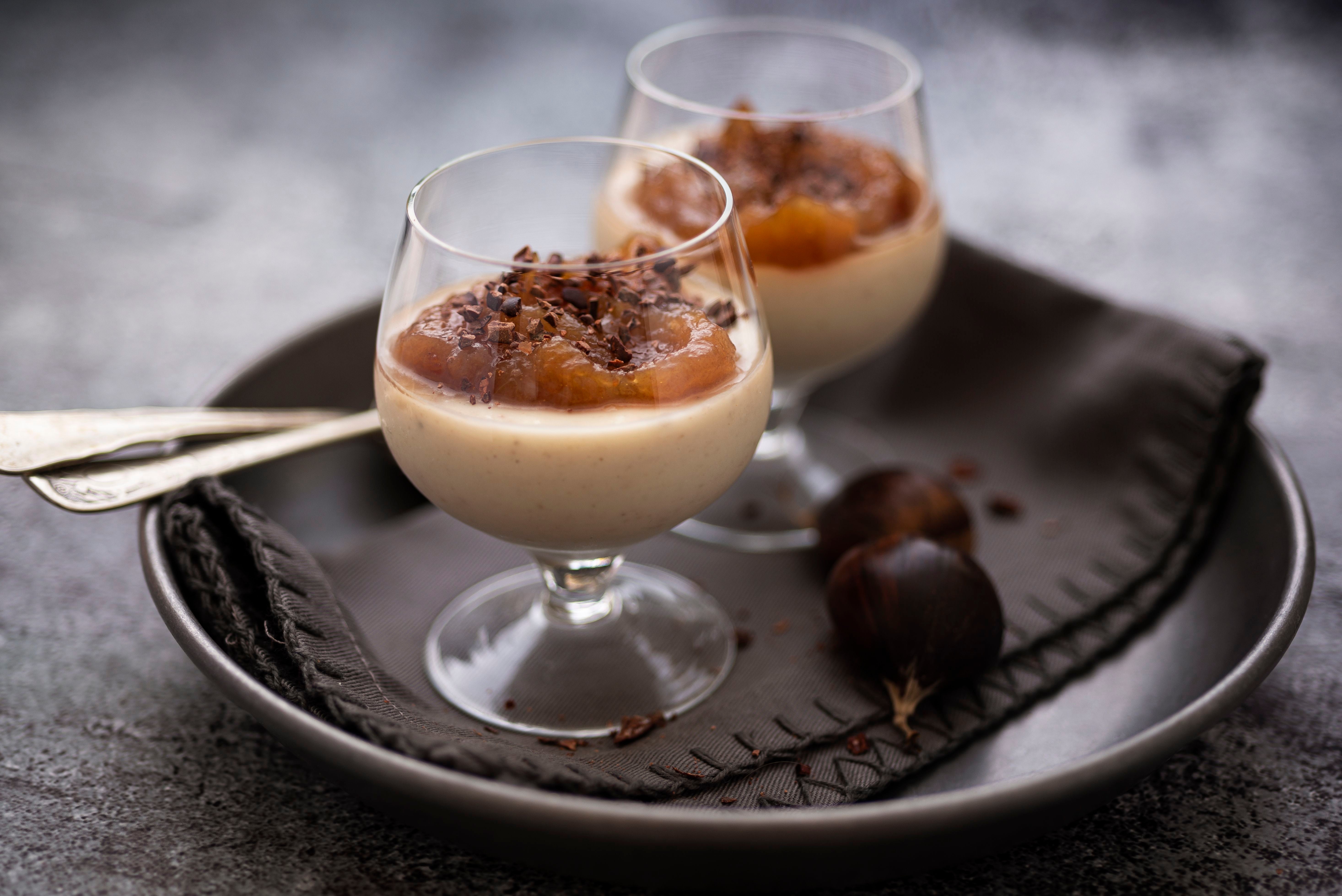 Zwei Gläser Dessert mit Kastaniencreme und Kompott auf einem dunklen Teller mit Serviette.