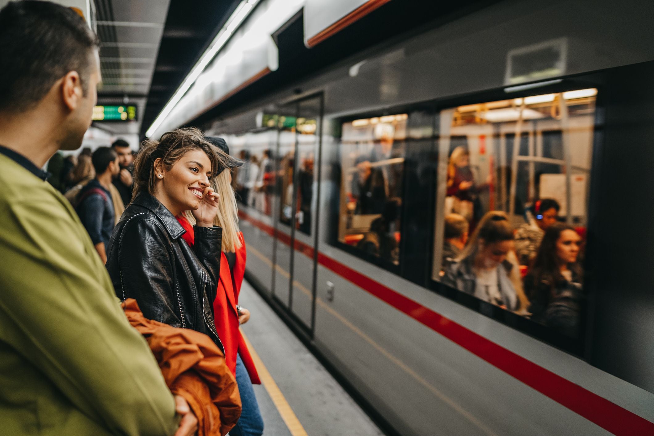 Junge Leute warten auf dem Bahnsteig einer U-Bahn-Station auf den einfahrenden Zug.