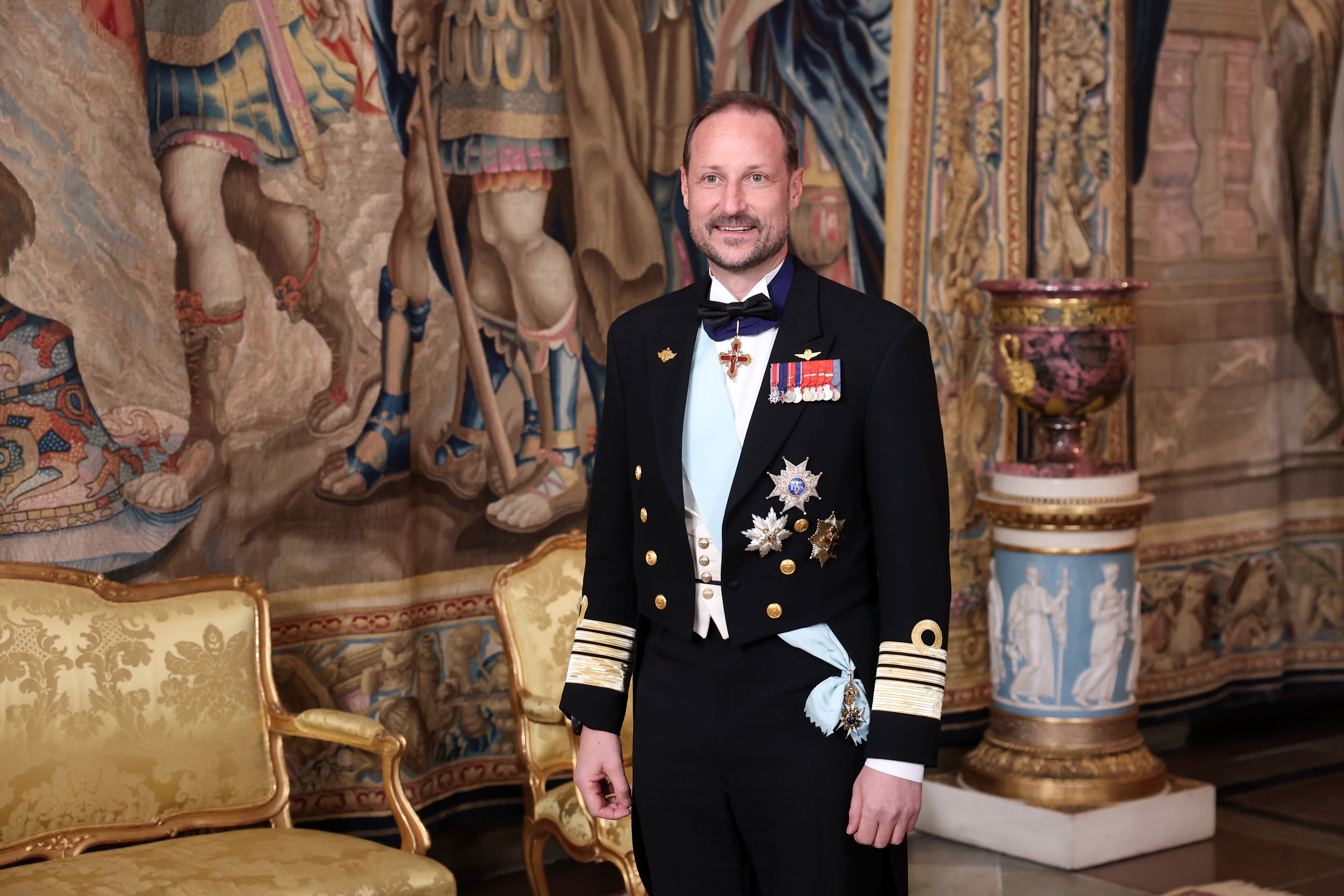 Ein Mann in Uniform sitzt auf einem goldenen Thron, daneben eine Frau in Schwarz; norwegische Flagge vorne.