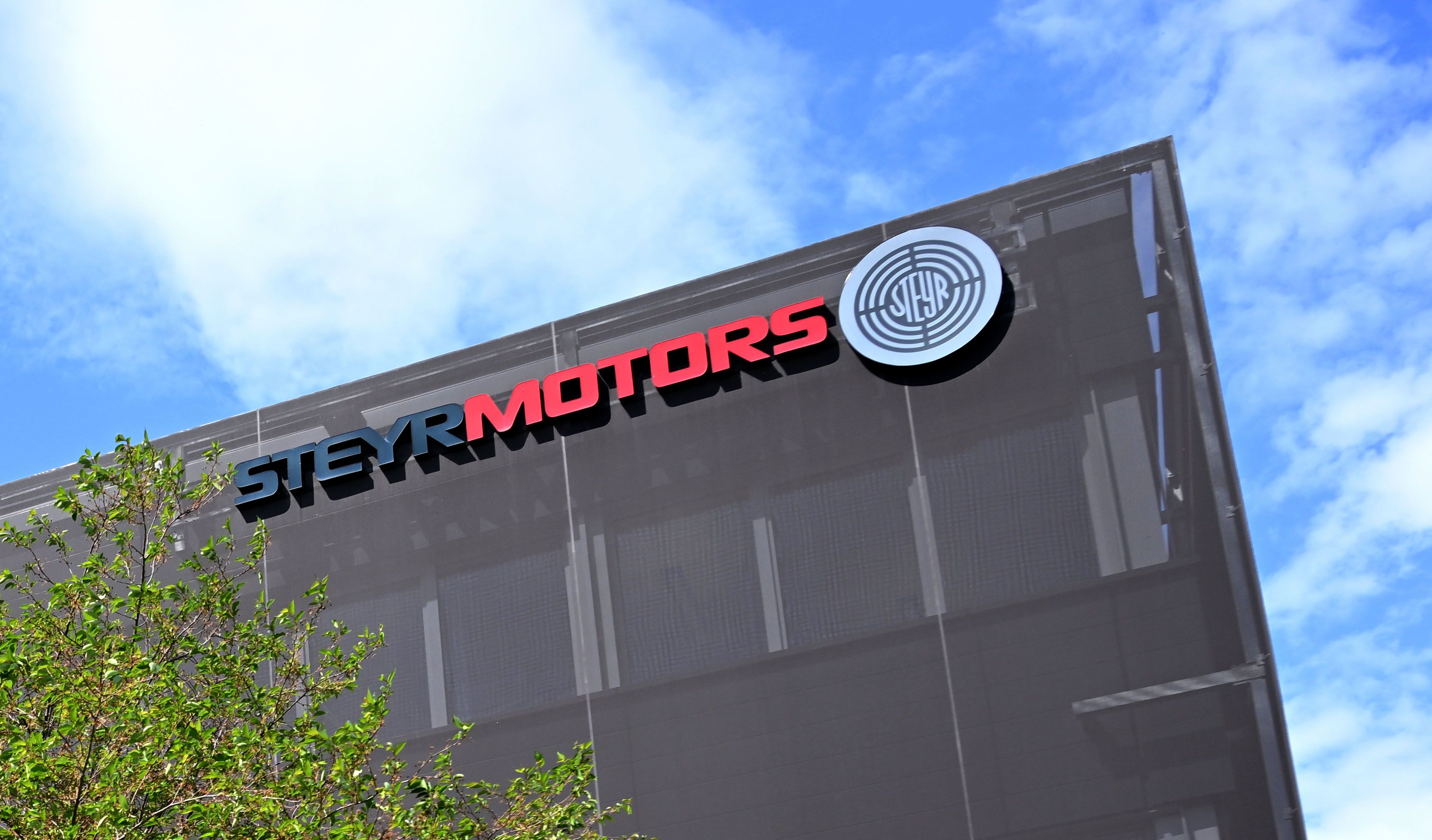 Das Logo von Steyr Motors an der Fassade des Firmengebäudes in Steyr bei blauem Himmel.