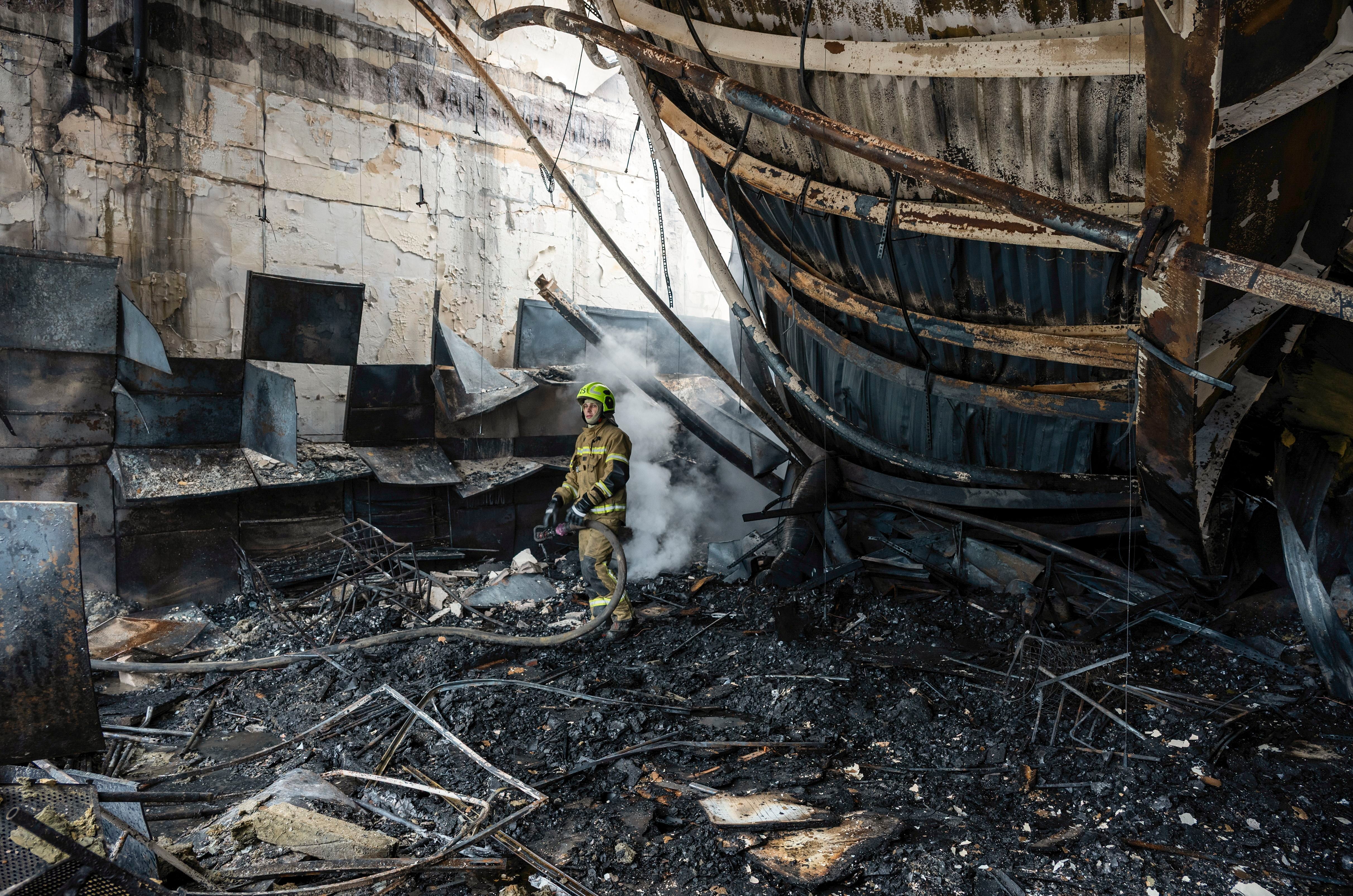 Ein Feuerwehrmann löscht Trümmer in einem ausgebrannten Gebäude nach einem Raketenangriff.