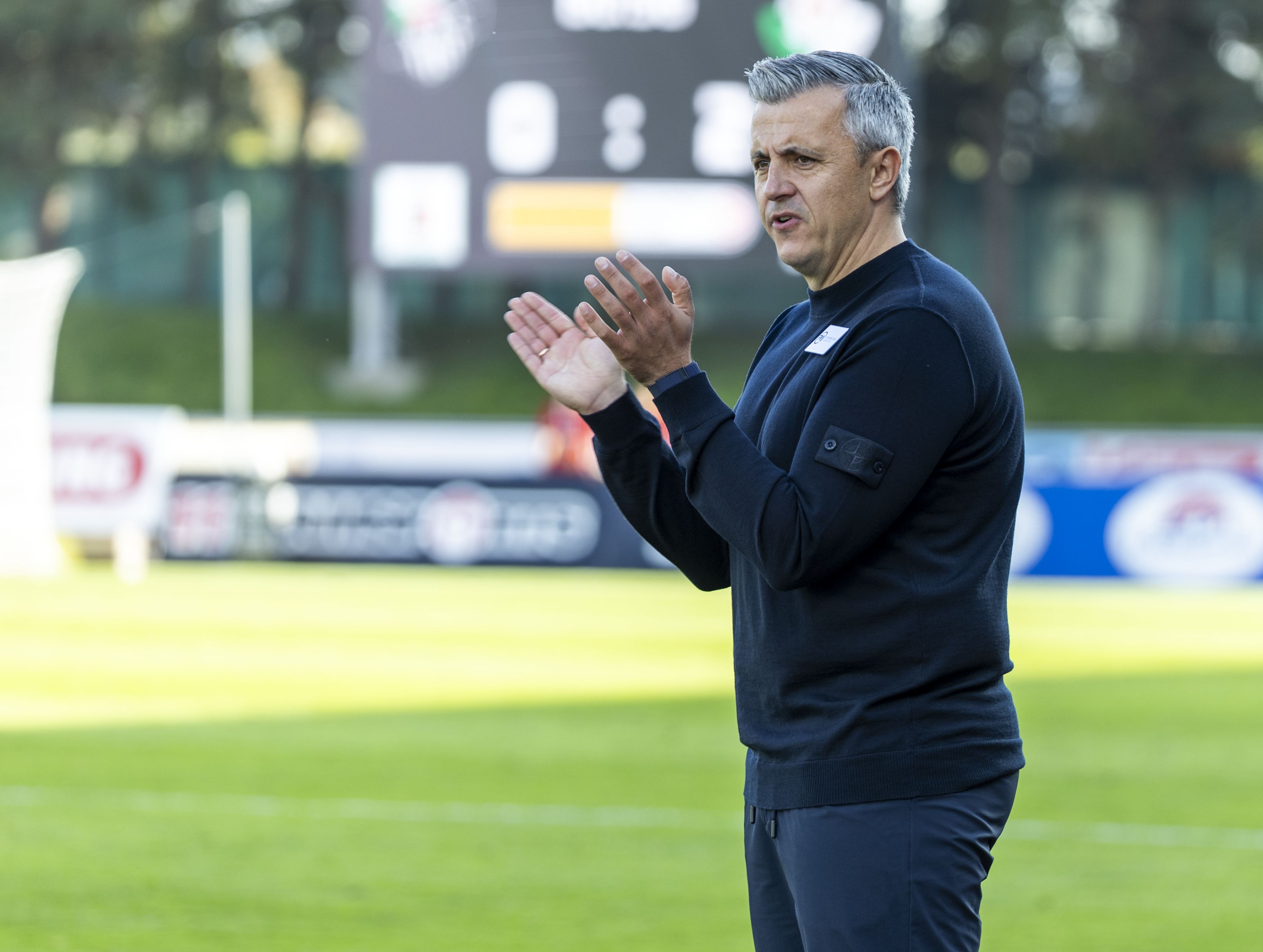 WSG-Tirol-Trainer Philipp Semlic klatscht im dunklen Pullover am Spielfeldrand Applaus.