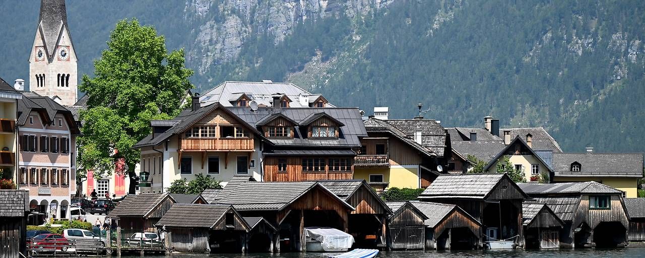 Häuser und Bootshäuser am Wasser in Hallstatt mit Bergen im Hintergrund.