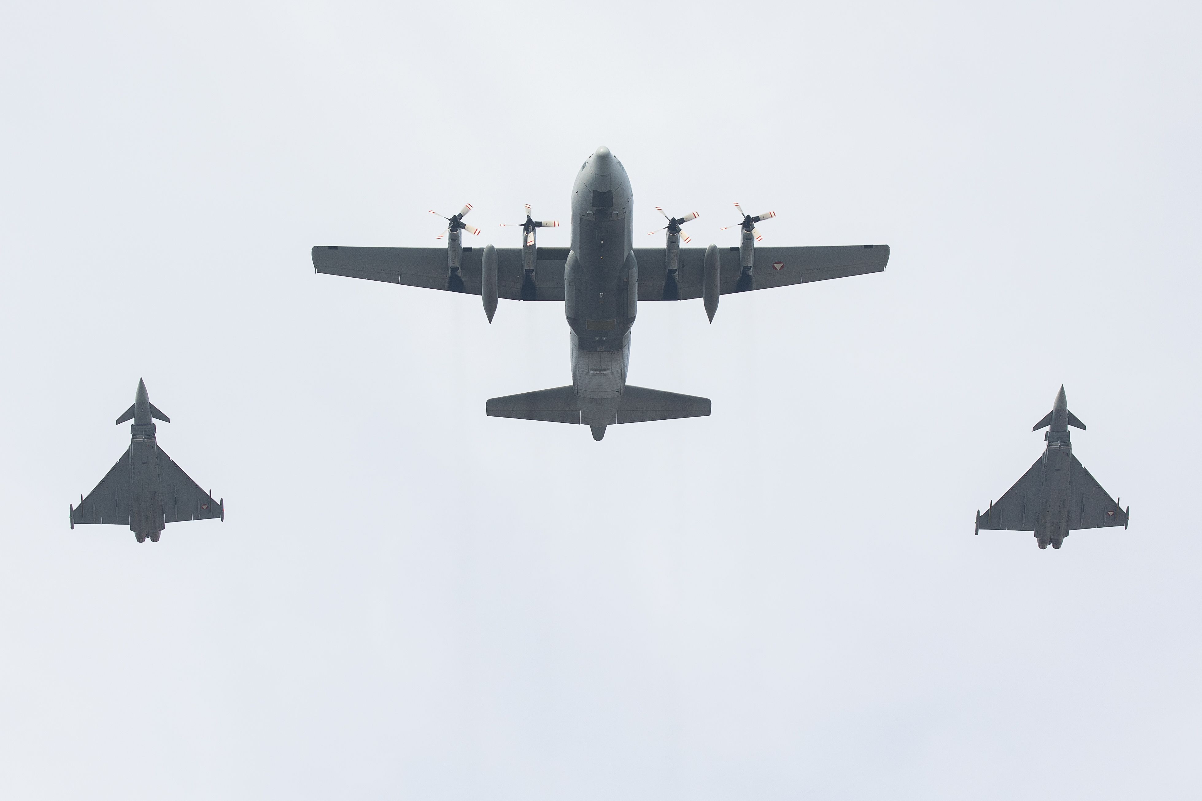 Drei Militärflugzeuge fliegen in Formation am Himmel, von unten gesehen.