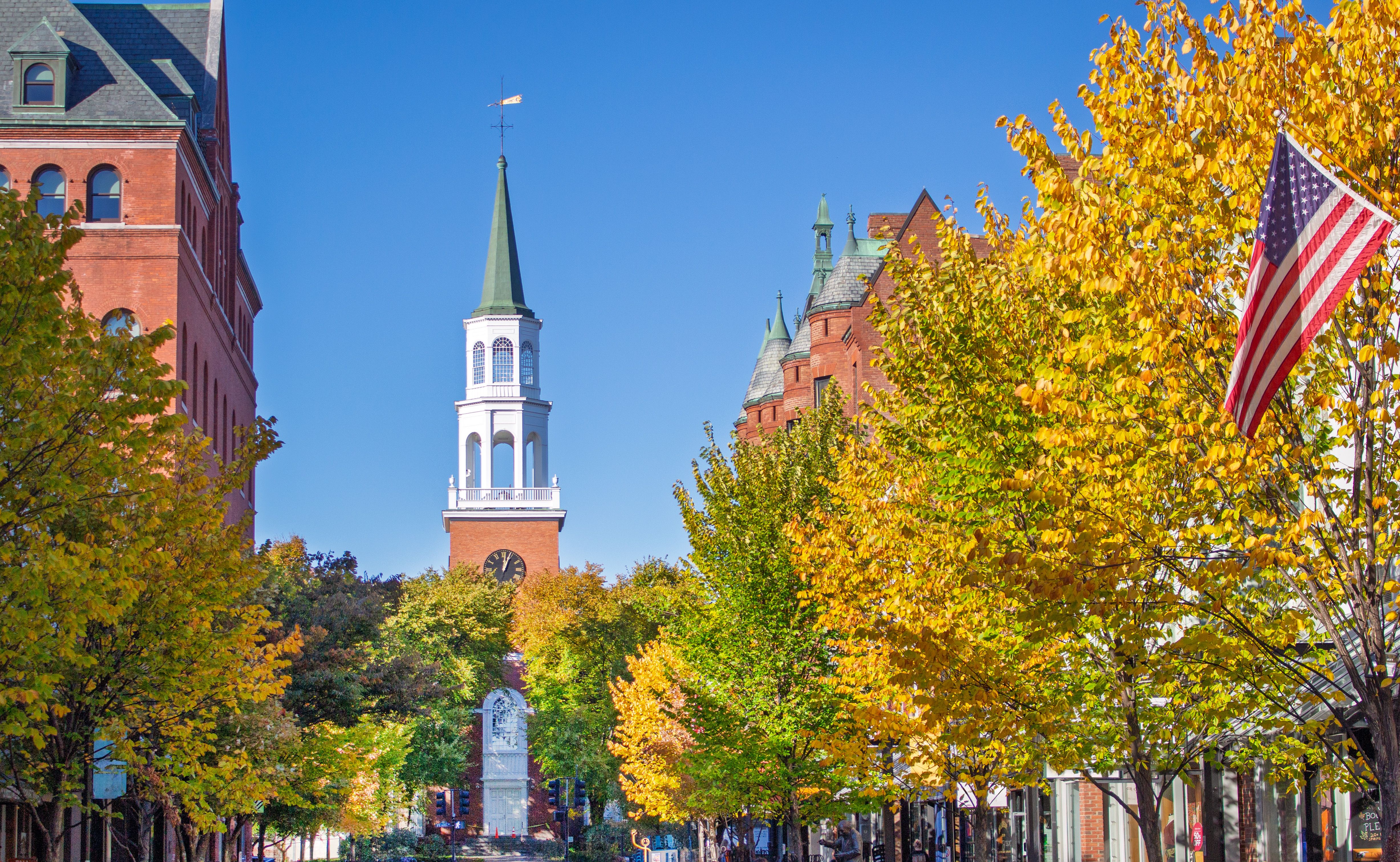 Herbstliche Straßenszene in Burlington mit bunter Laubfärbung und Kirchturm im Hintergrund.