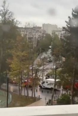 Straßenszene in Paris mit Einsatzfahrzeugen und Bäumen an einem bewölkten Tag.
