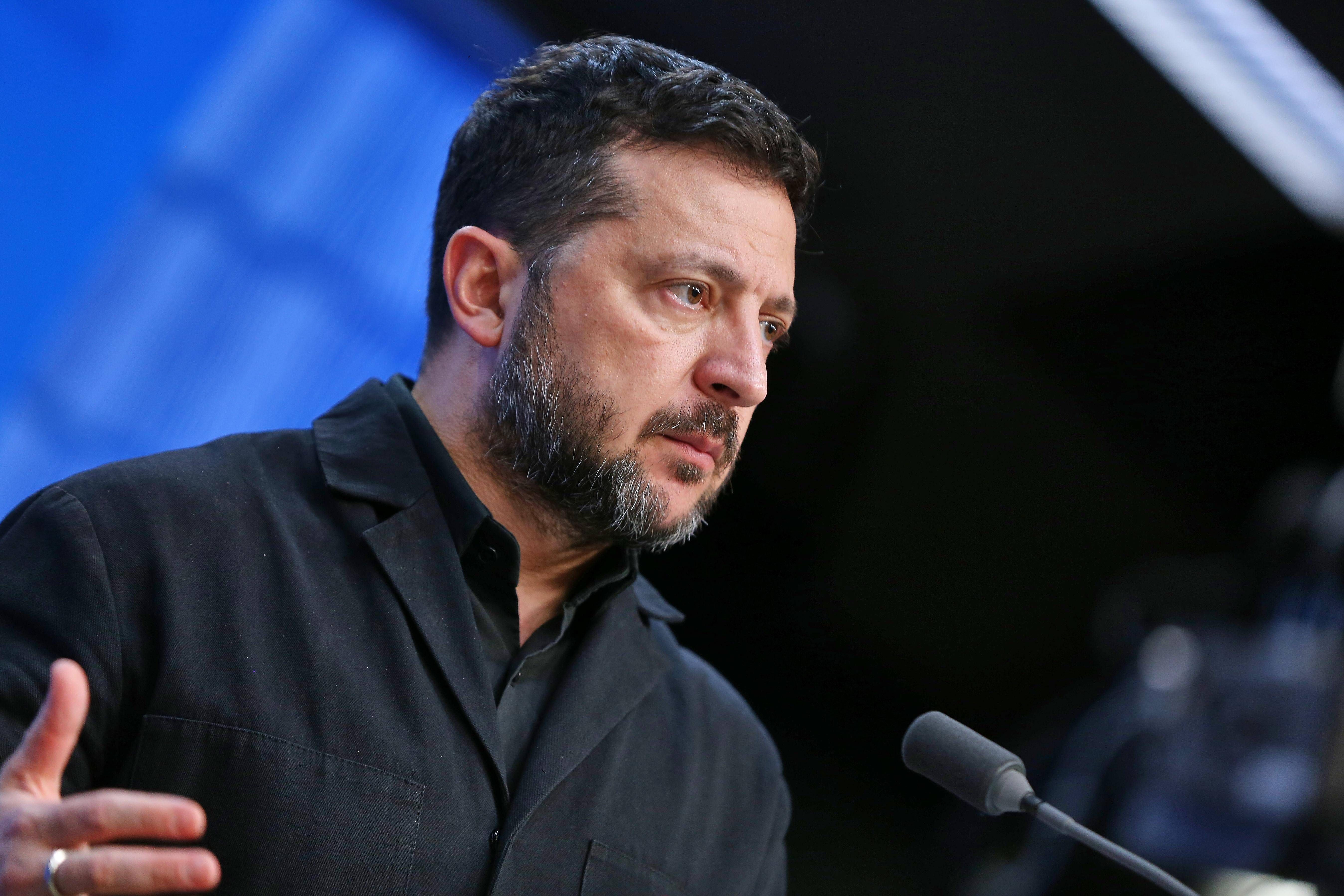 Ein Mann mit Bart spricht auf einer Pressekonferenz vor Mikrofonen.