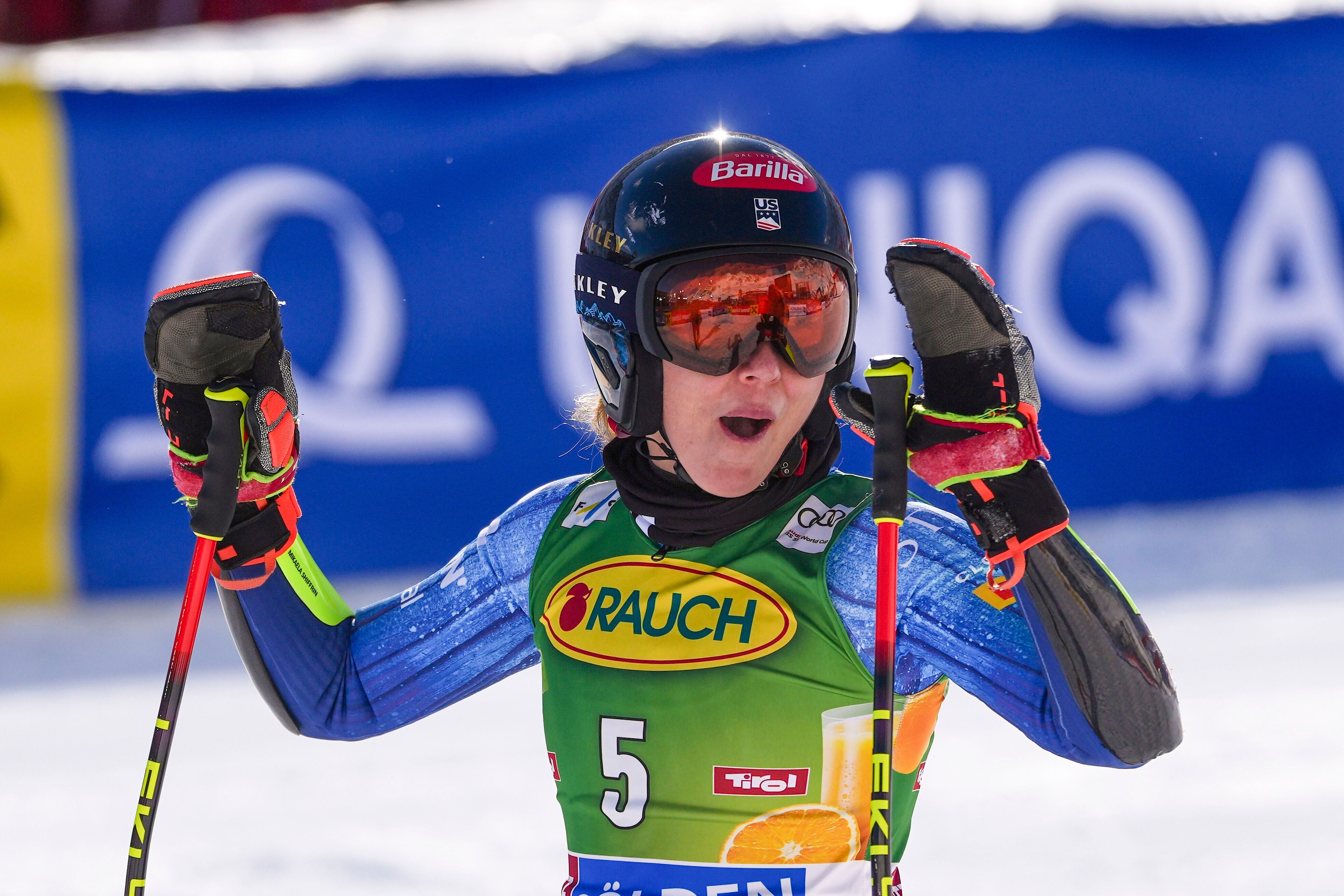 Skirennläuferin jubelt im Ziel mit erhobenen Armen, Helm und Skibrille.