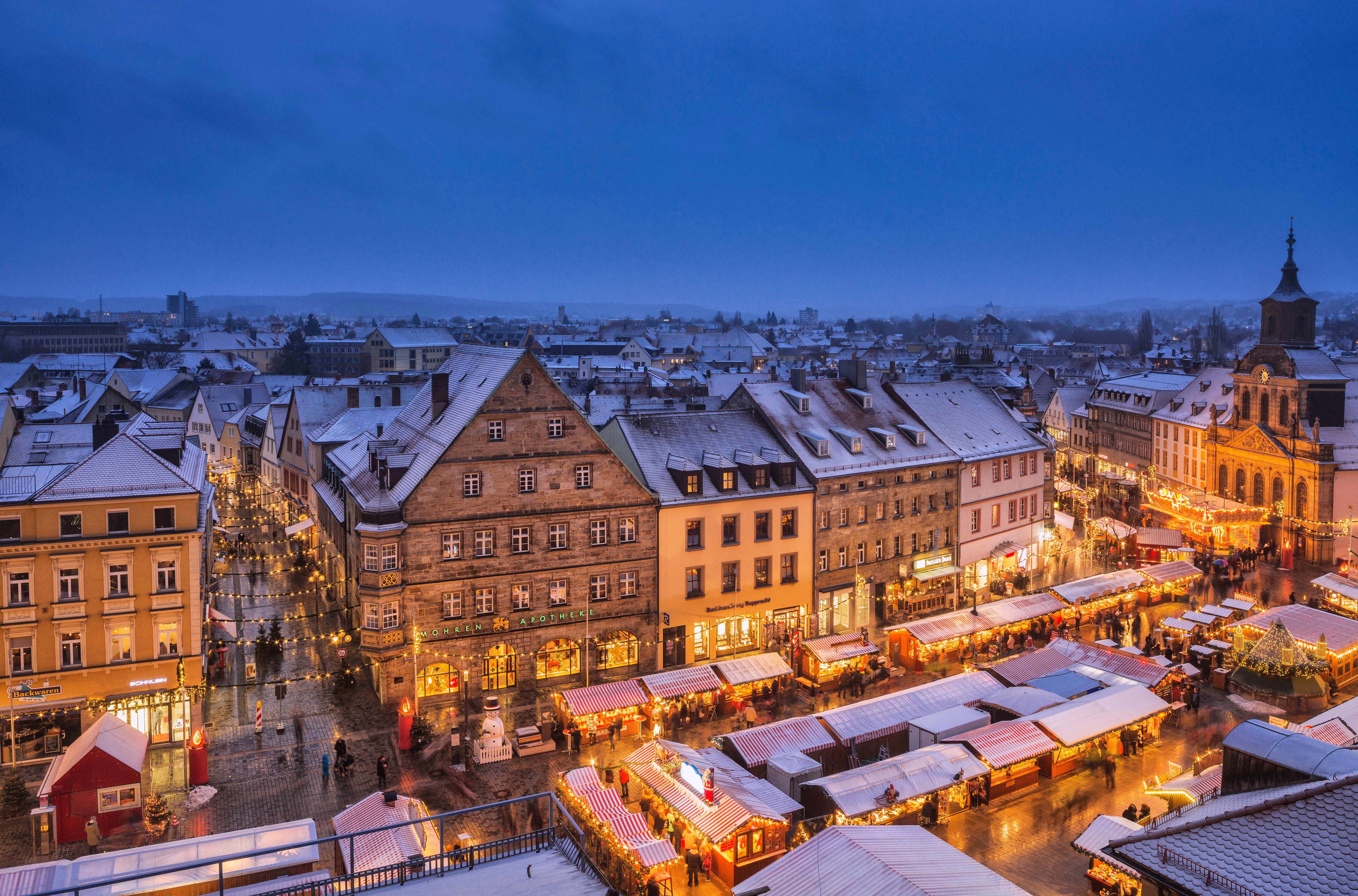 Verschneiter Weihnachtsmarkt in der Innenstadt von Bayreuth bei abendlicher Dämmerung.