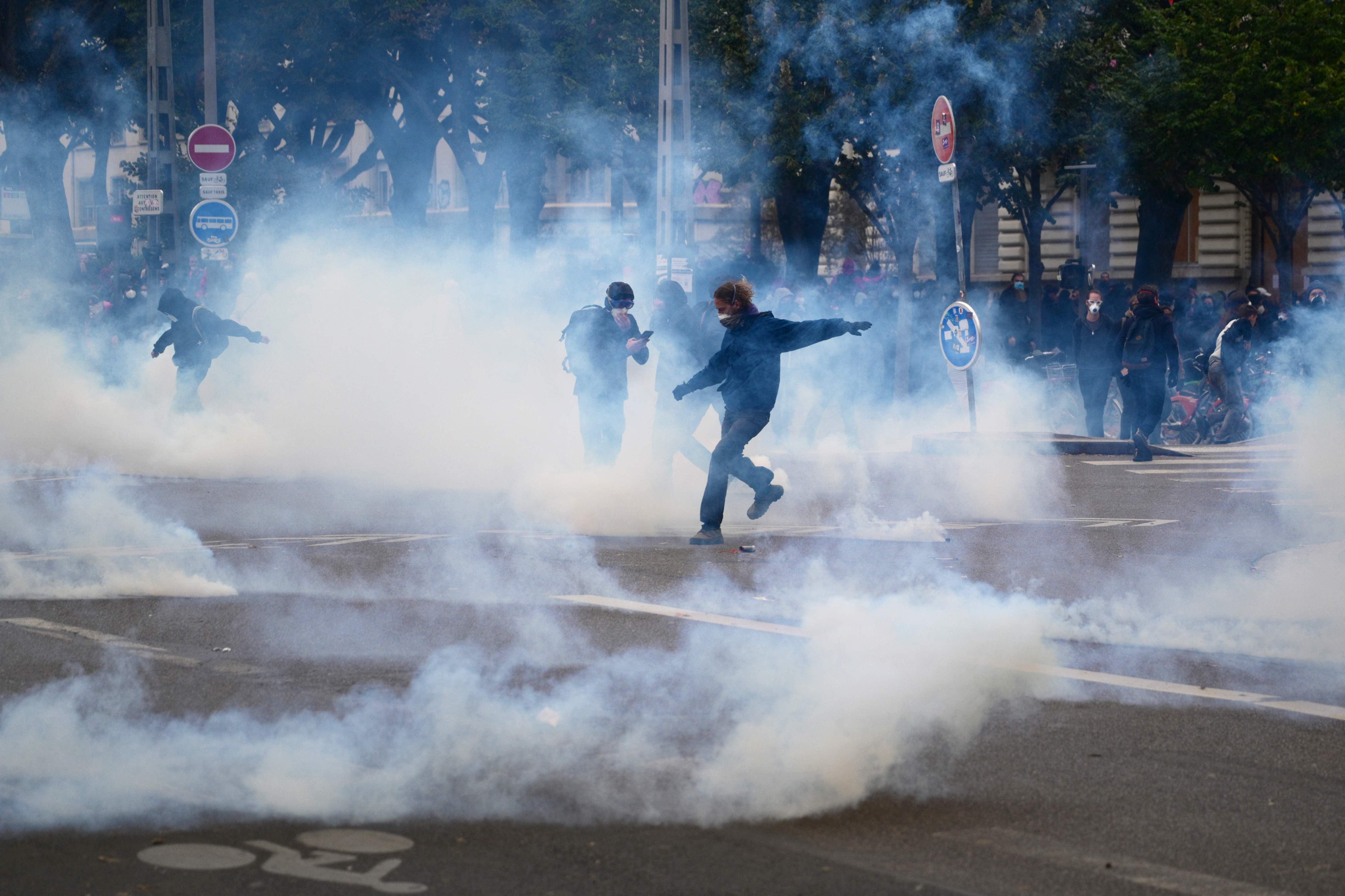 Demonstranten laufen durch Tränengaswolken während eines Protests auf einer Straße in Lyon.