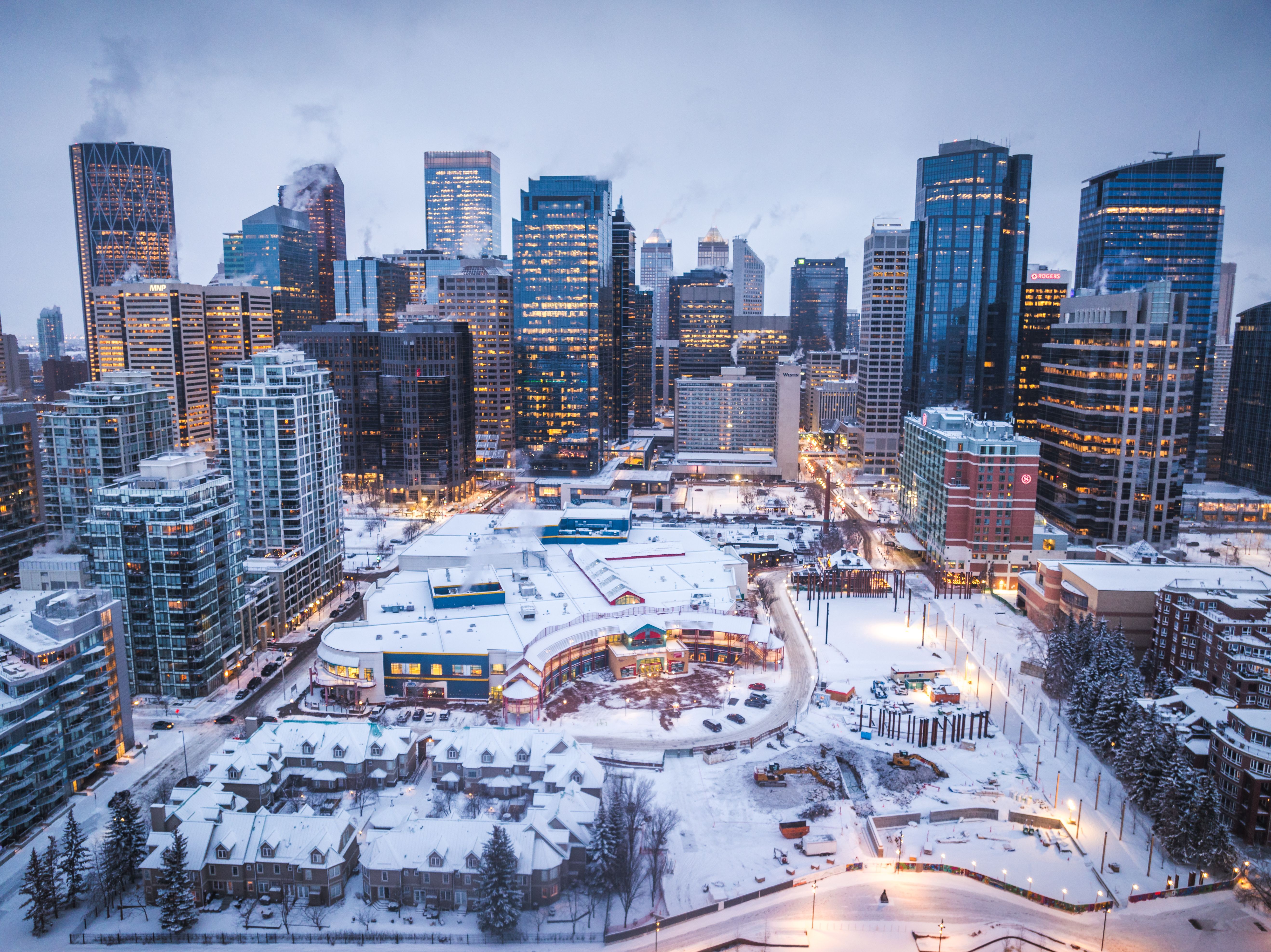 Verschneite Innenstadt von Calgary mit beleuchteten Hochhäusern in der Abenddämmerung.
