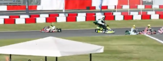 Ein Kart überschlägt sich auf der Rennstrecke, mehrere Karts und Fahrer sind zu sehen.