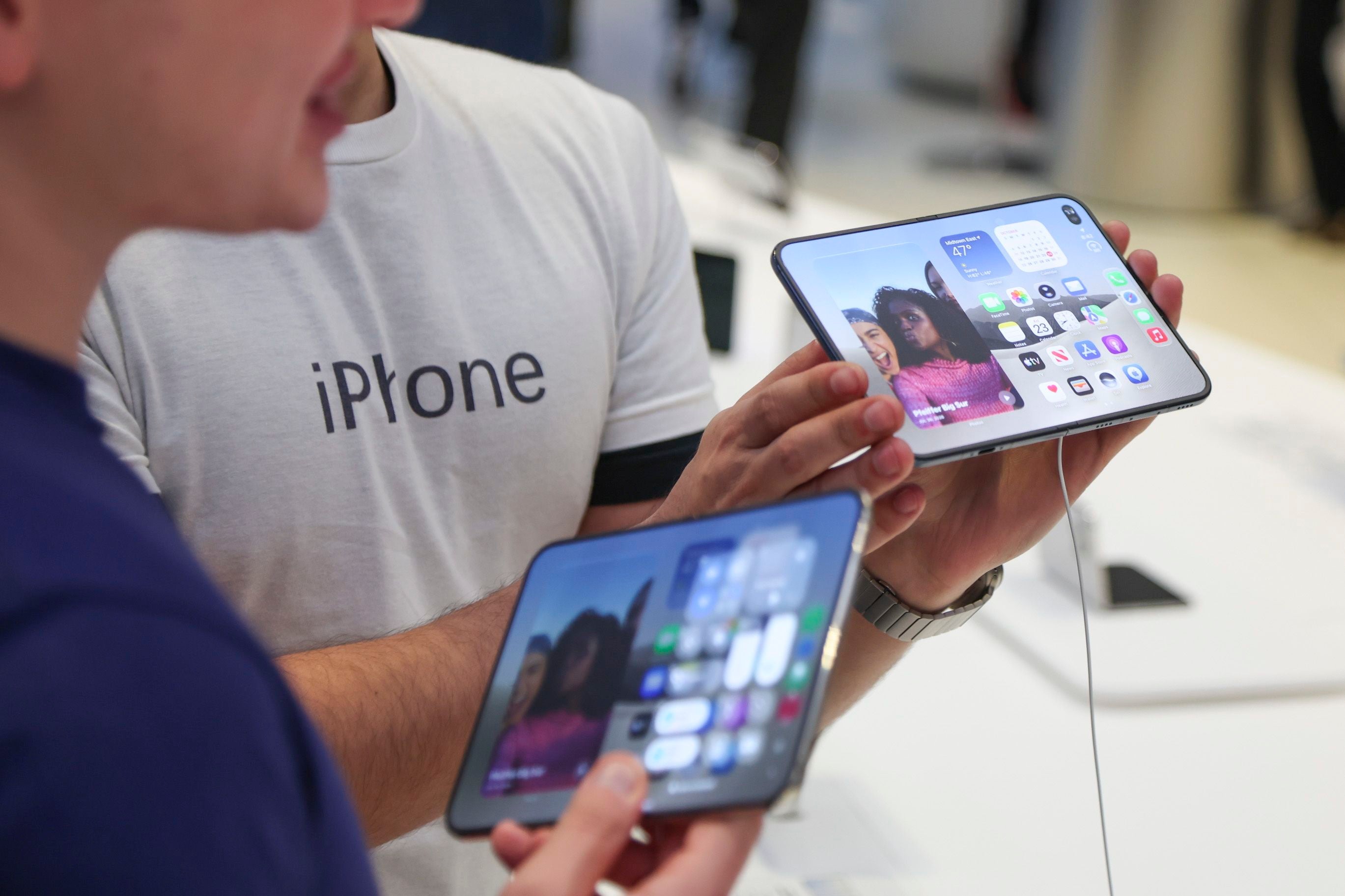 Zwei Personen testen im Apple Store ein faltbares iPhone Duo mit großem Display.