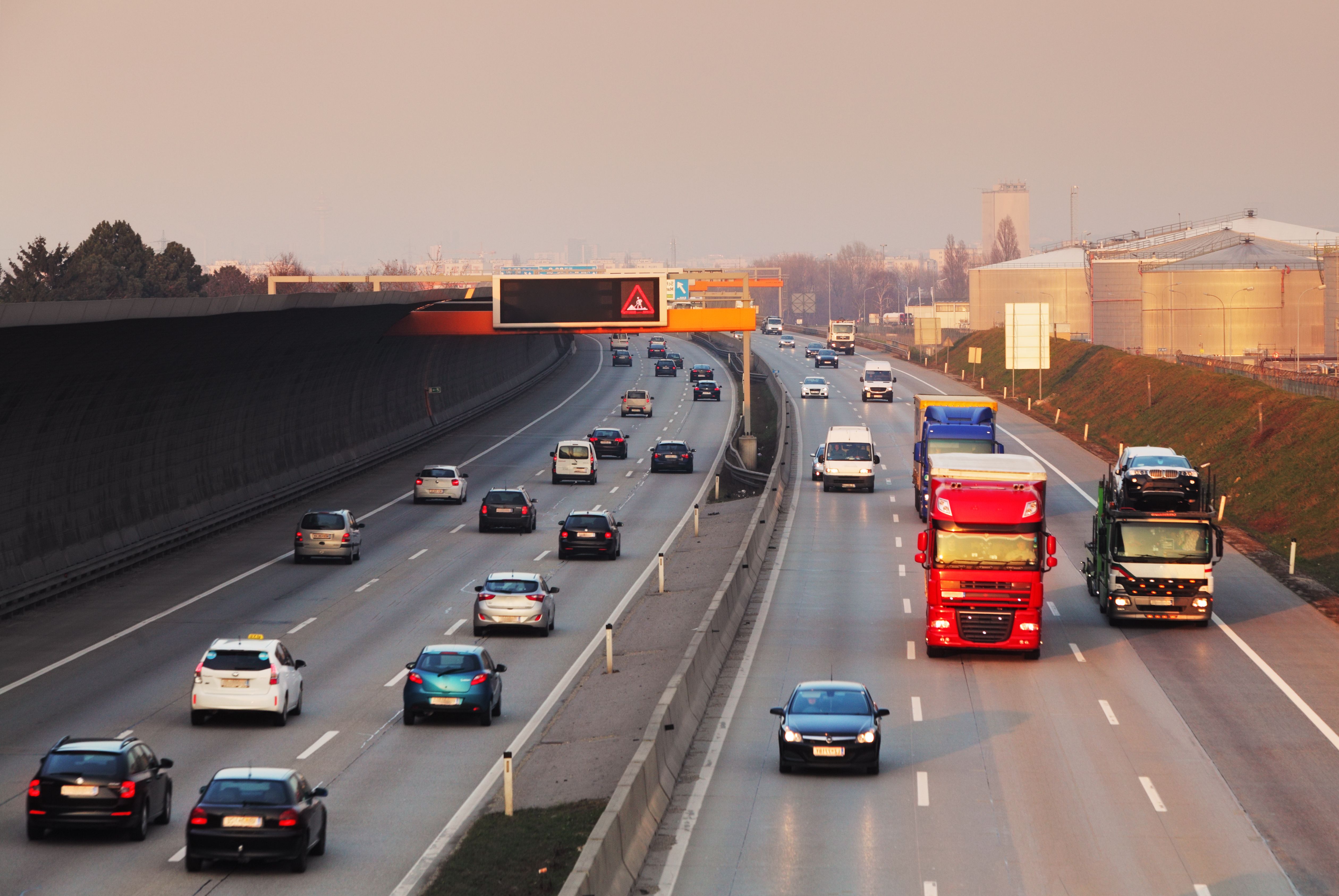 Mehrspurige Autobahn mit Autos und Lkw bei mäßigem Verkehr in beide Richtungen.