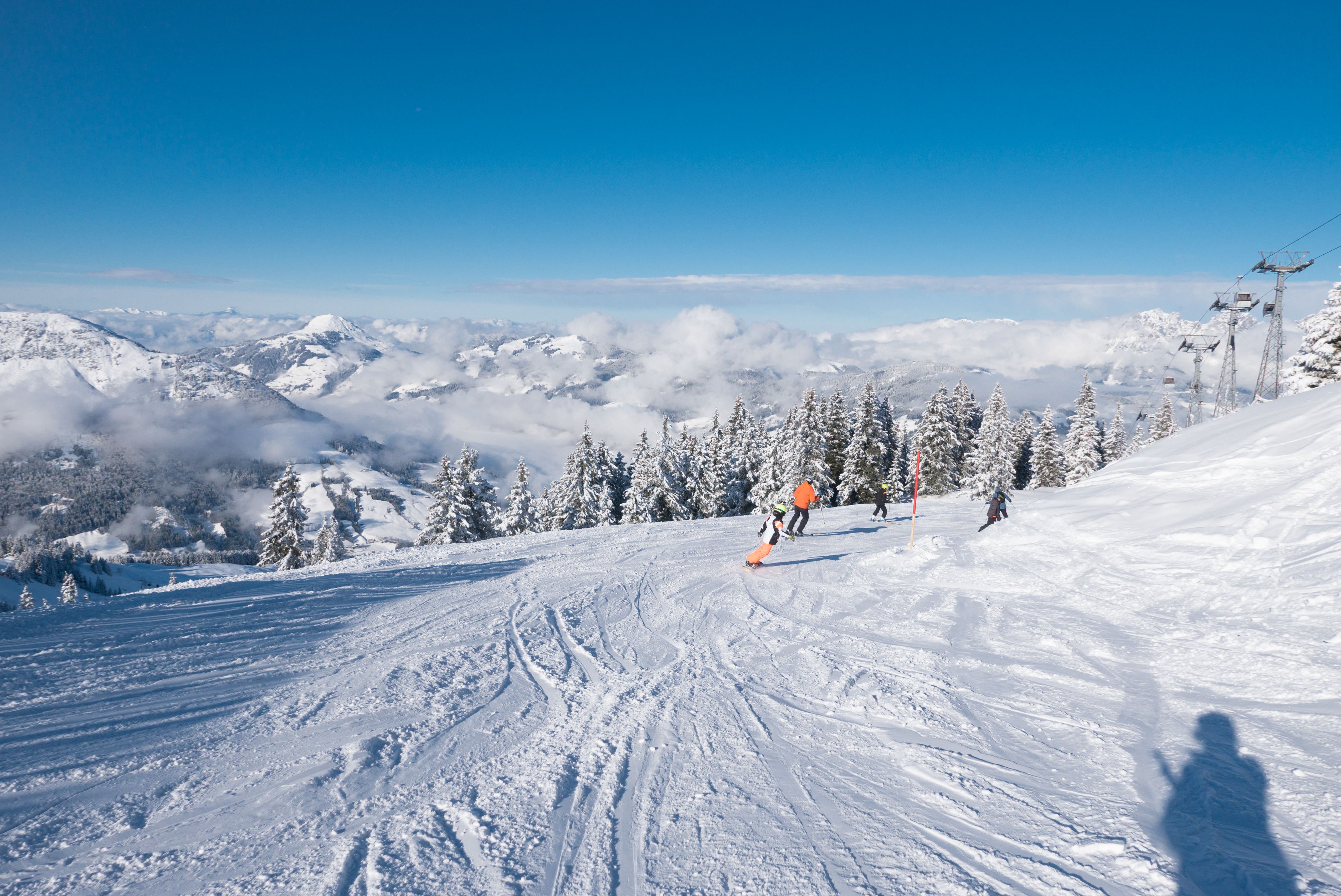 Snowboarder auf verschneiter Piste mit Bergpanorama im Skigebiet Kitzbühel, Österreich.
