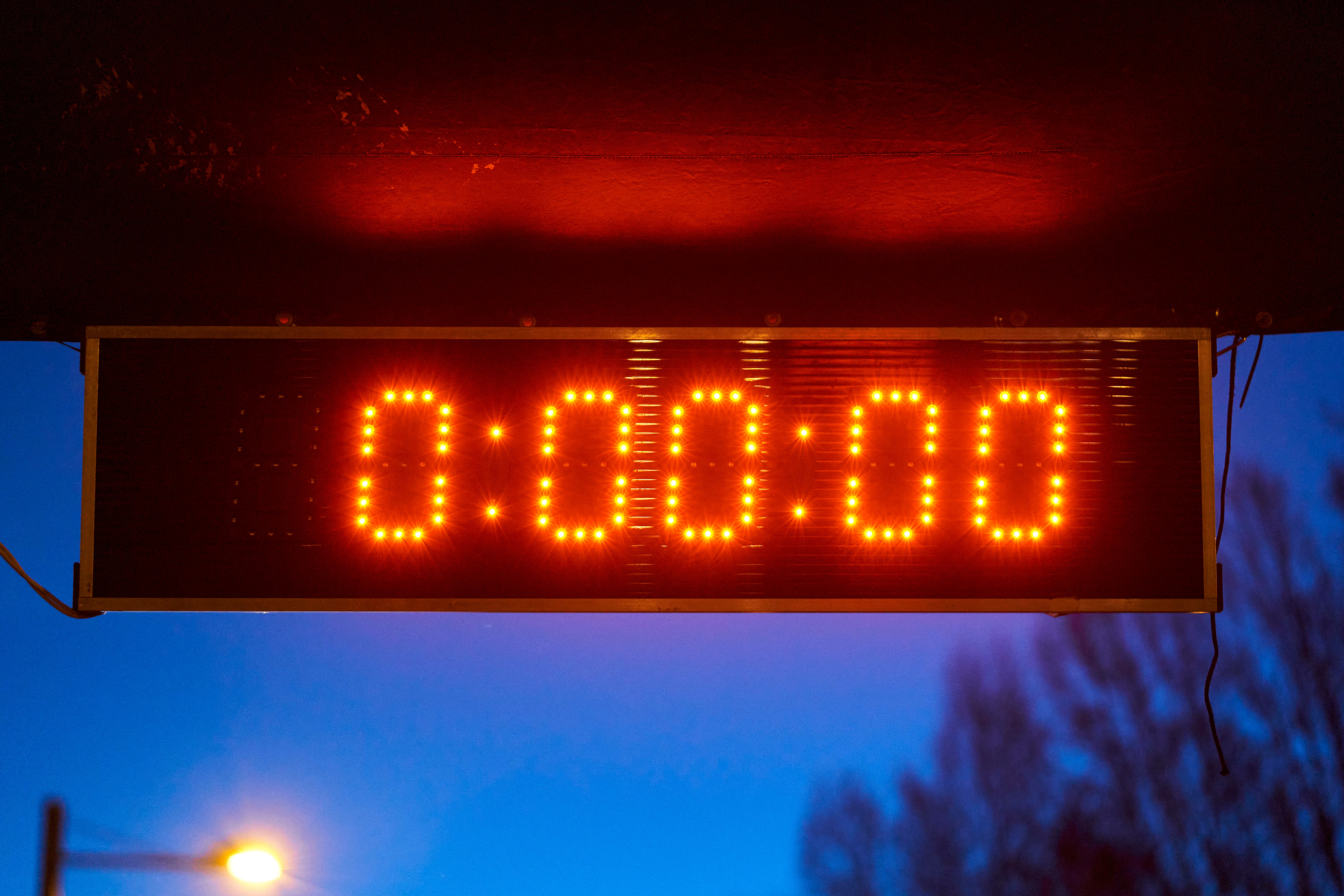 Digitale Anzeigetafel zeigt 0:00:00 in rot, Hintergrund ist dämmerig mit Straßenlaterne.