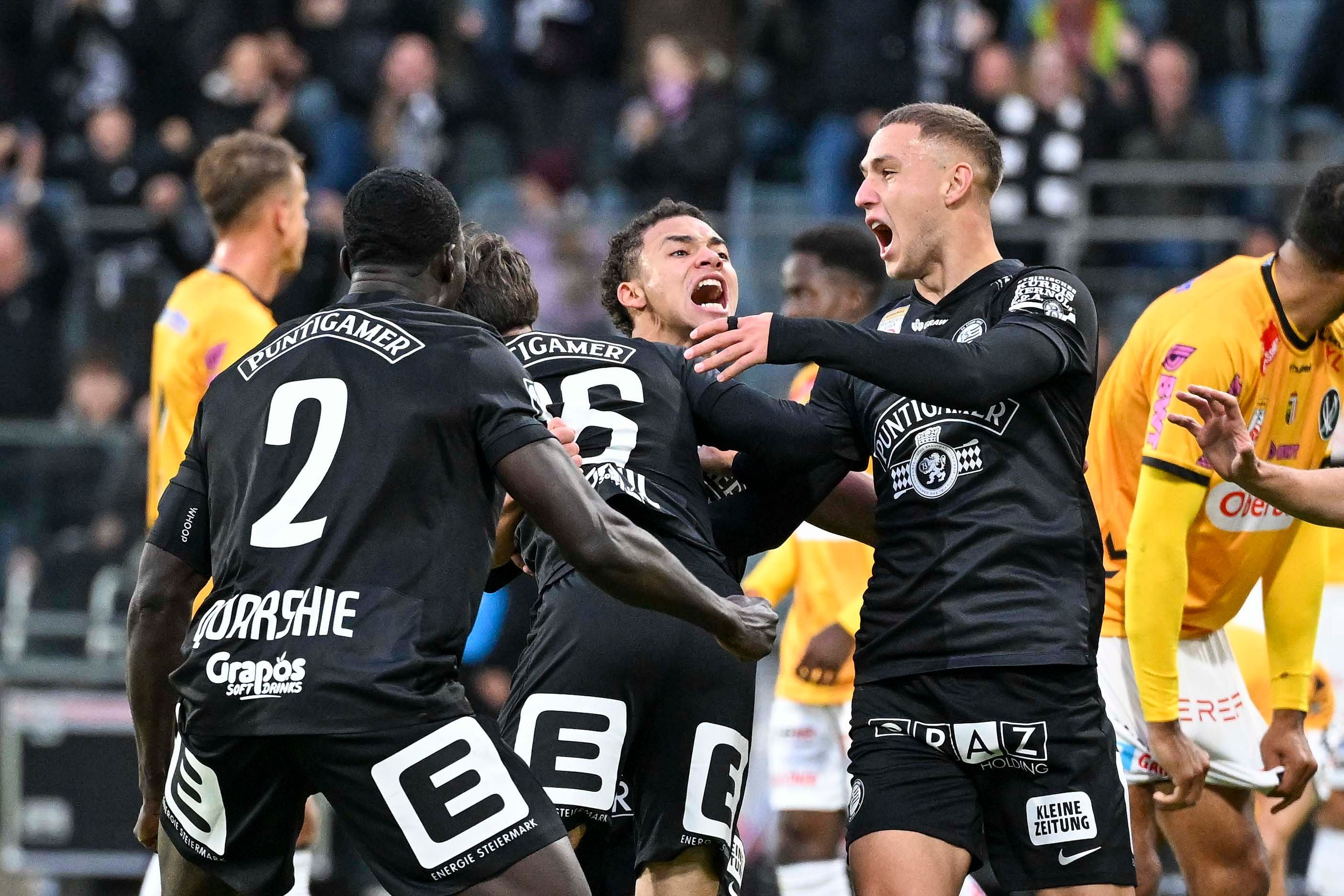 Fußballspieler von Sturm Graz jubeln nach einem Tor, andere Spieler im Hintergrund.