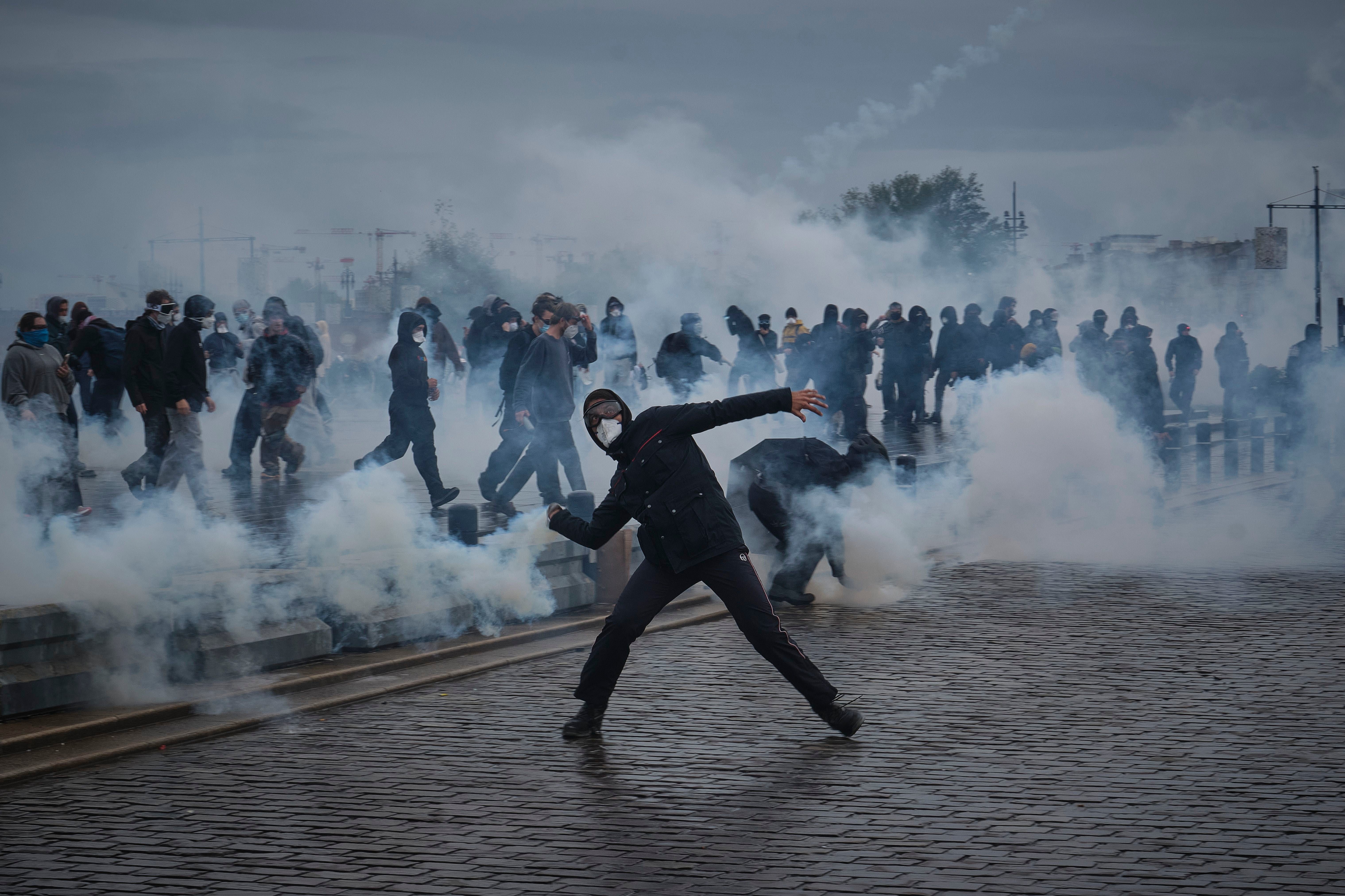 Menschen demonstrieren in Bordeaux, während Tränengas auf einer Straße eingesetzt wird.