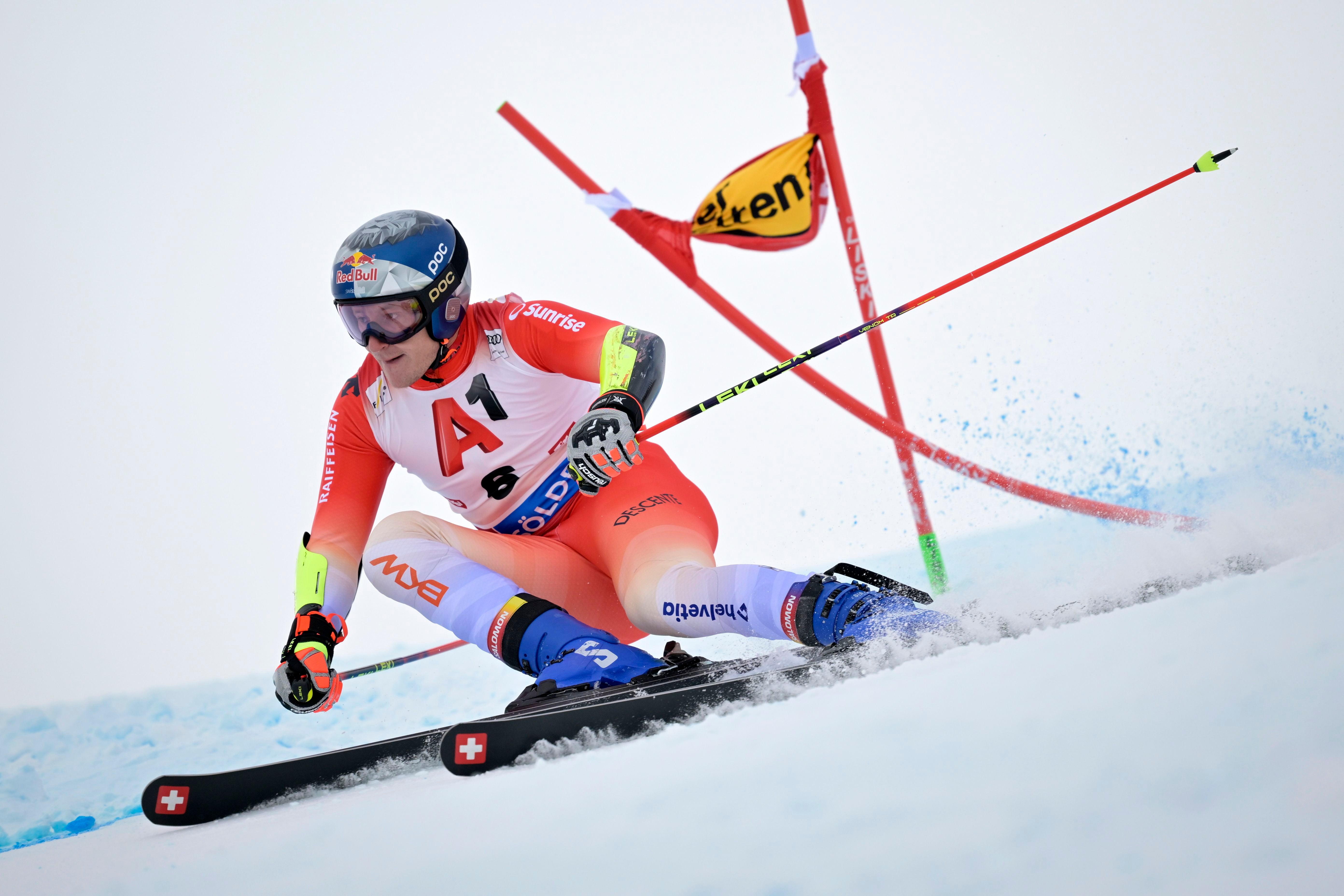 Ein Skirennfahrer fährt im Riesenslalom an einem Tor auf einer schneebedeckten Piste vorbei.