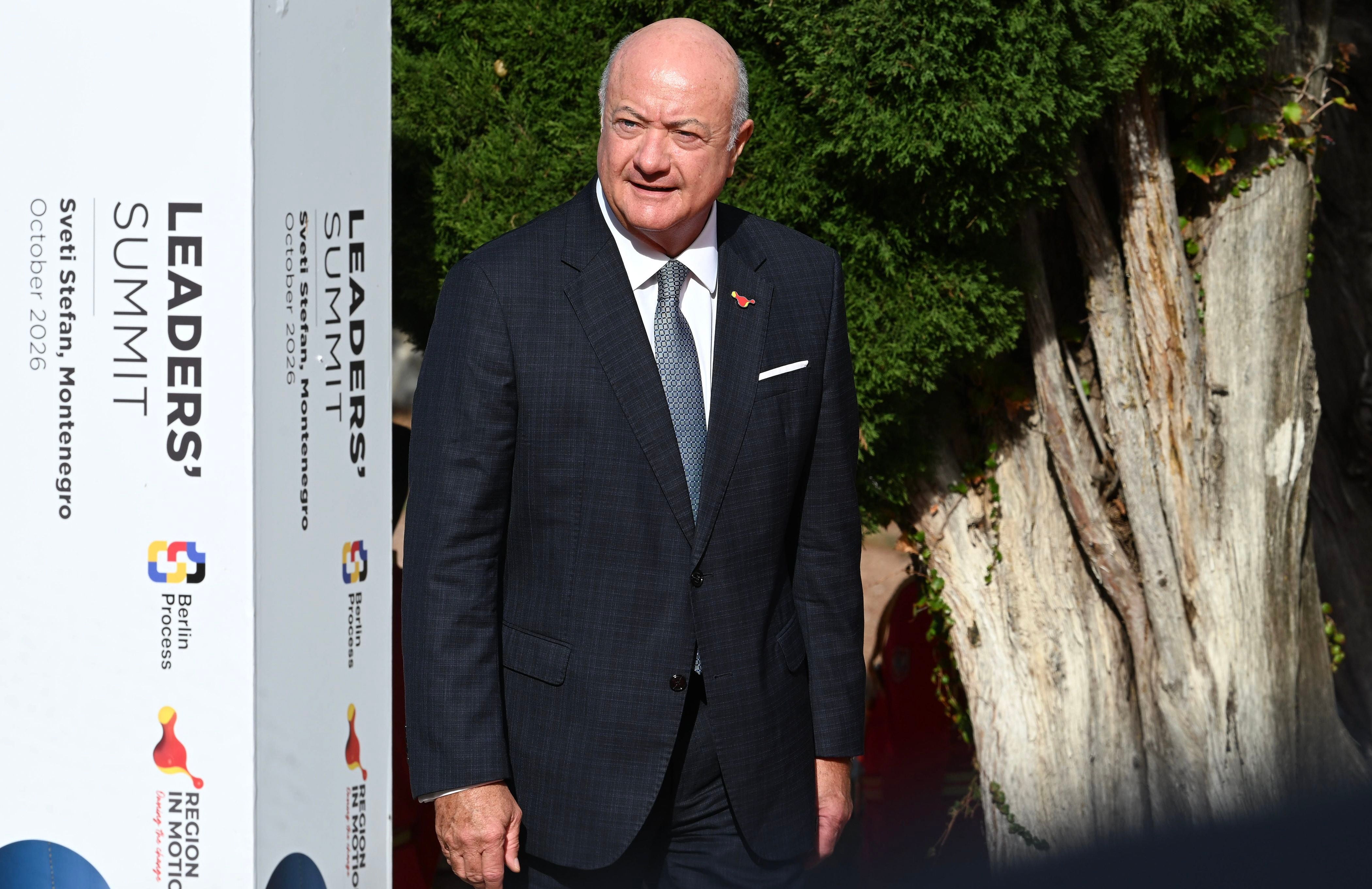 Ein Mann im Anzug steht vor einem Schild des Leaders' Summit in Montenegro im Freien.