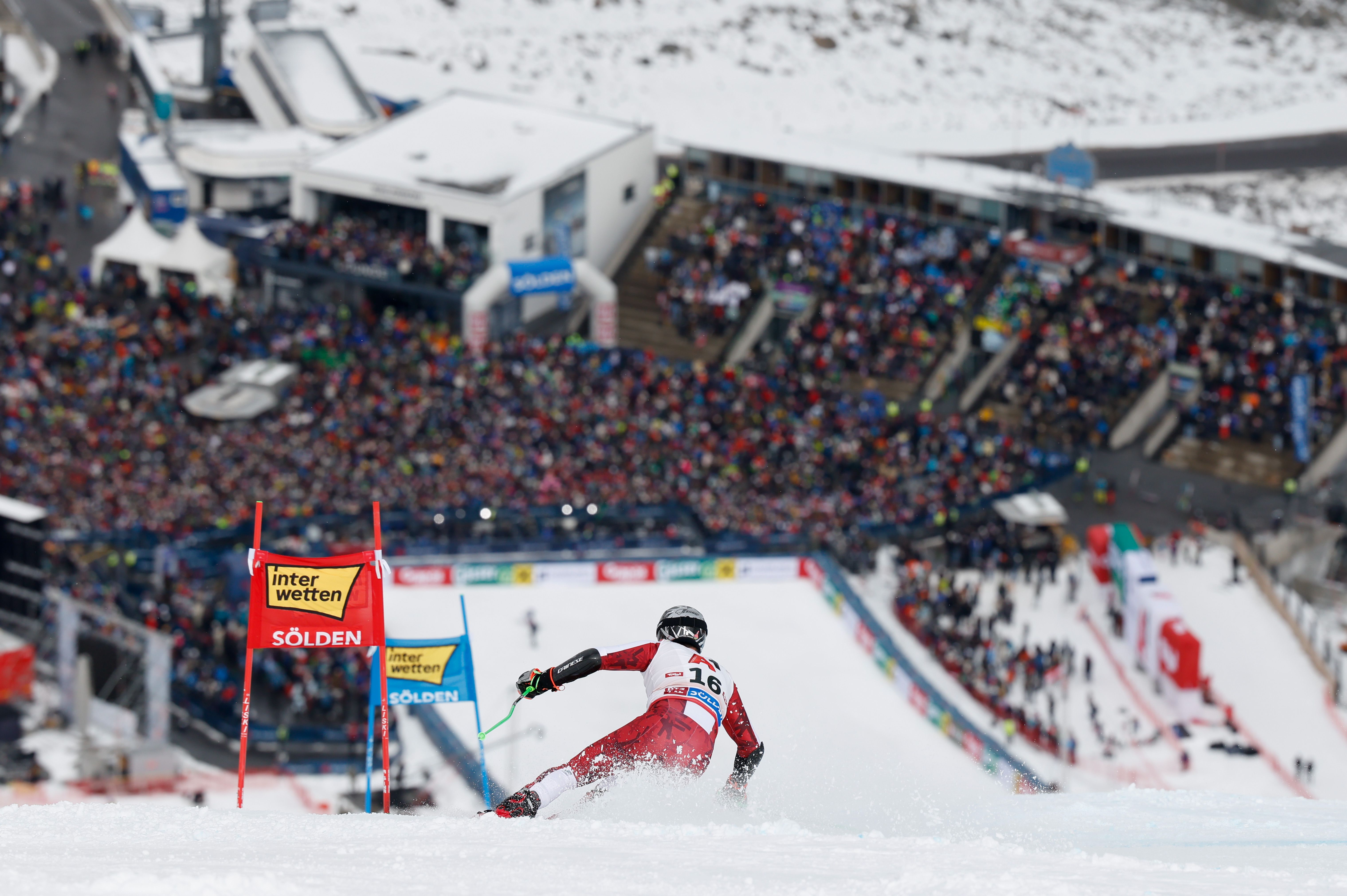 Skifahrer fährt beim Riesenslalom in Sölden vor einer großen Zuschauermenge bergab.