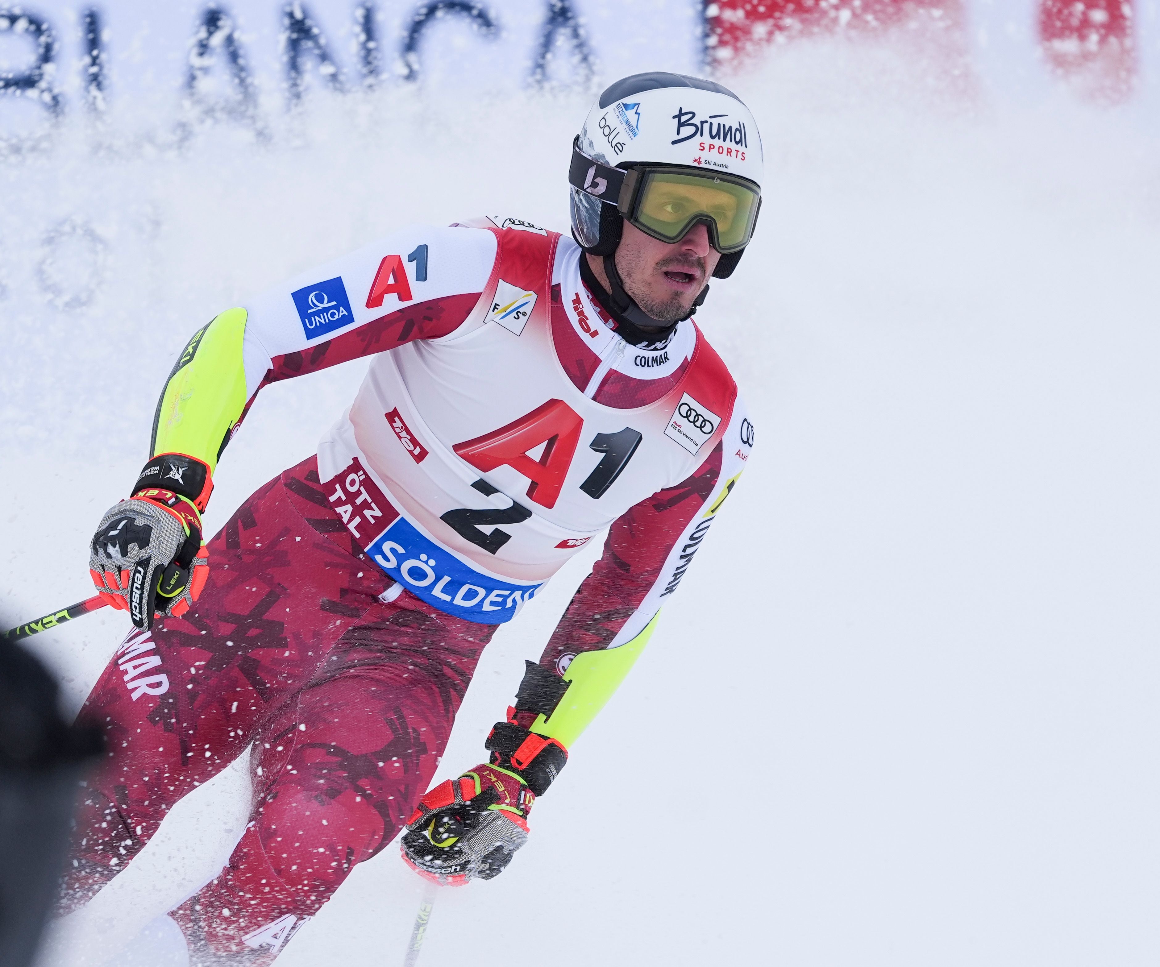 Ein Skirennläufer im roten Anzug beim Riesenslalom auf einer verschneiten Piste.