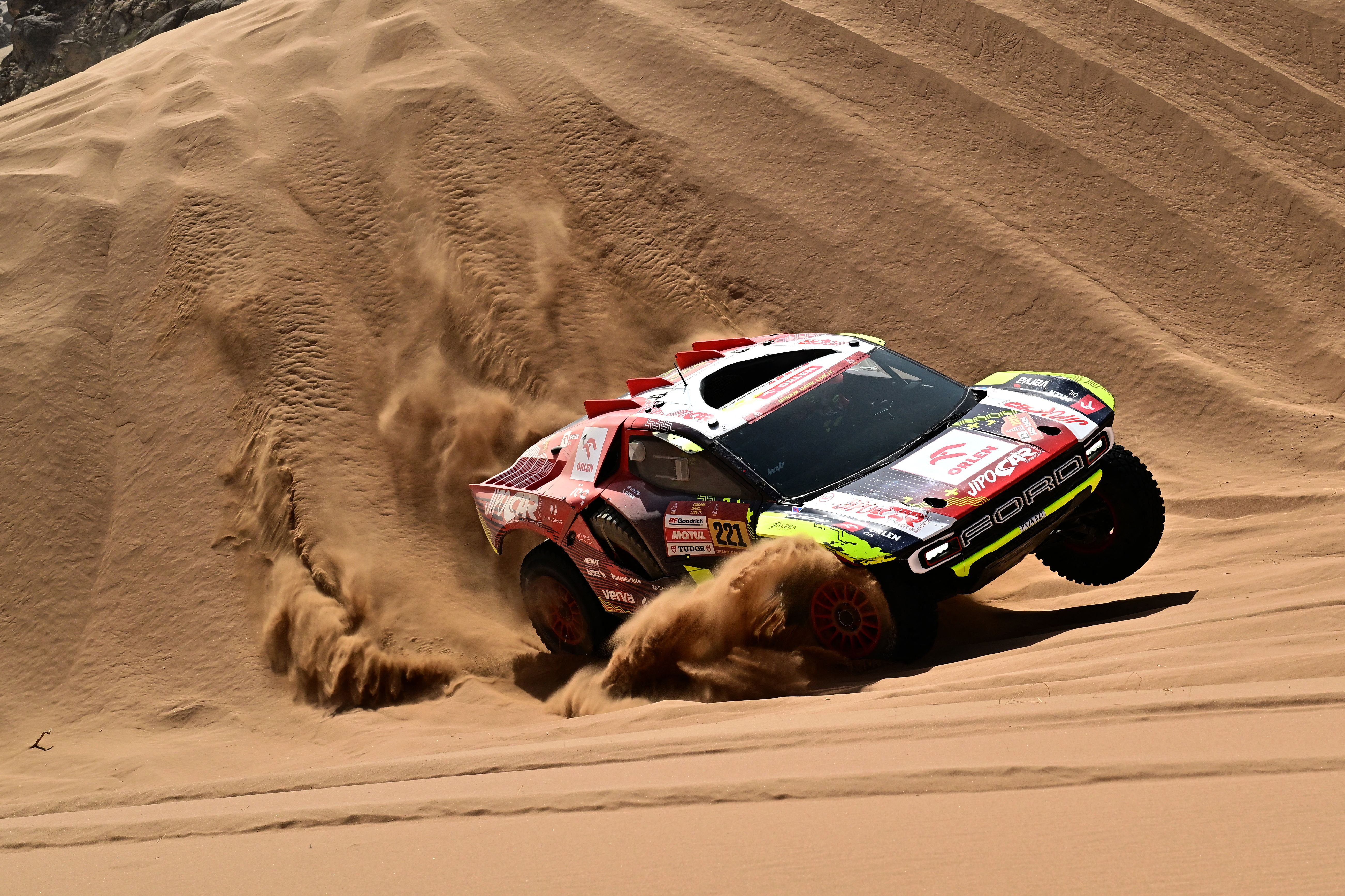 Rennwagen fährt durch Sanddüne während der Dakar Rallye in Saudi-Arabien.