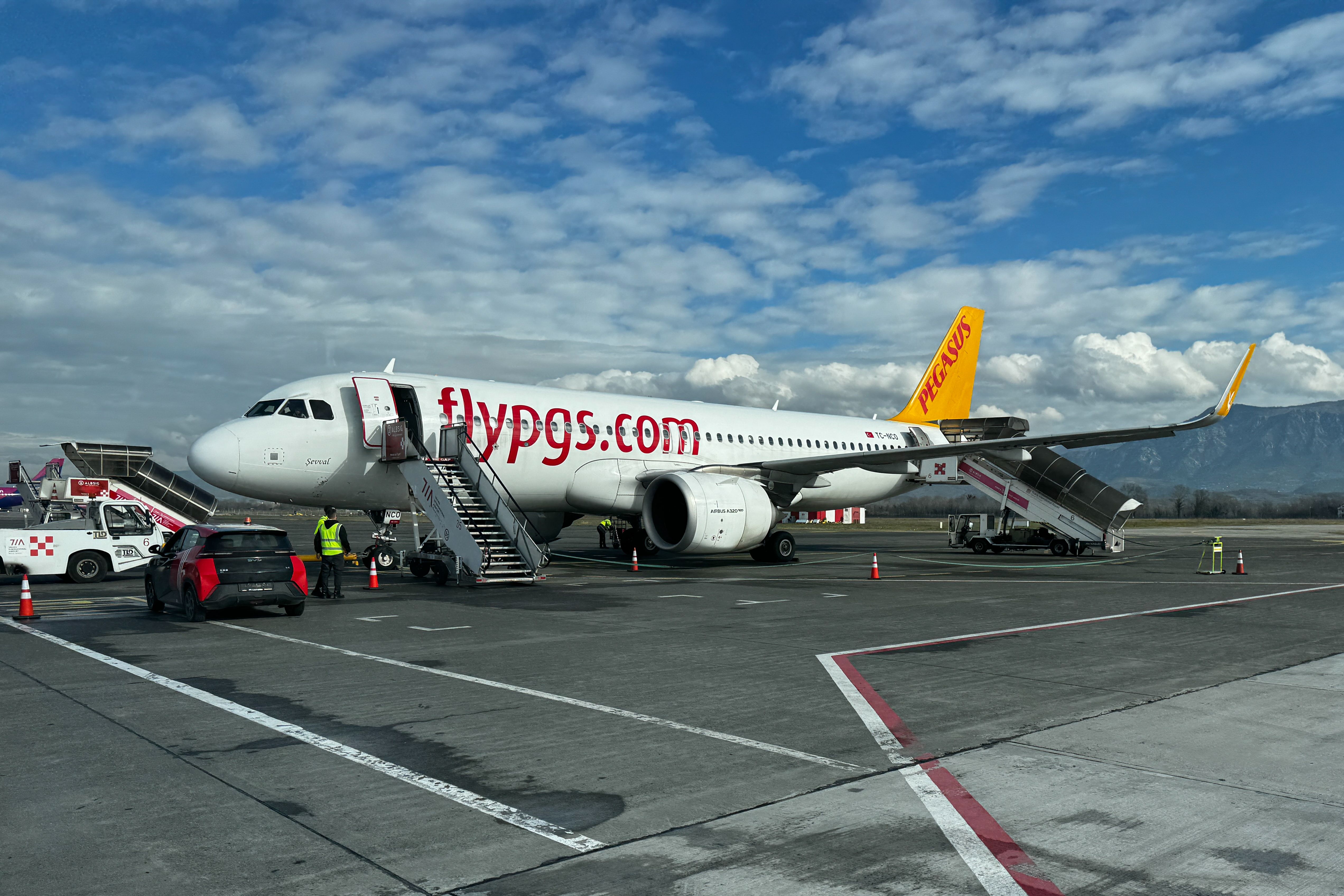 Pegasus Airlines Flugzeug steht mit Treppen am Tirana International Airport unter blauem Himmel.