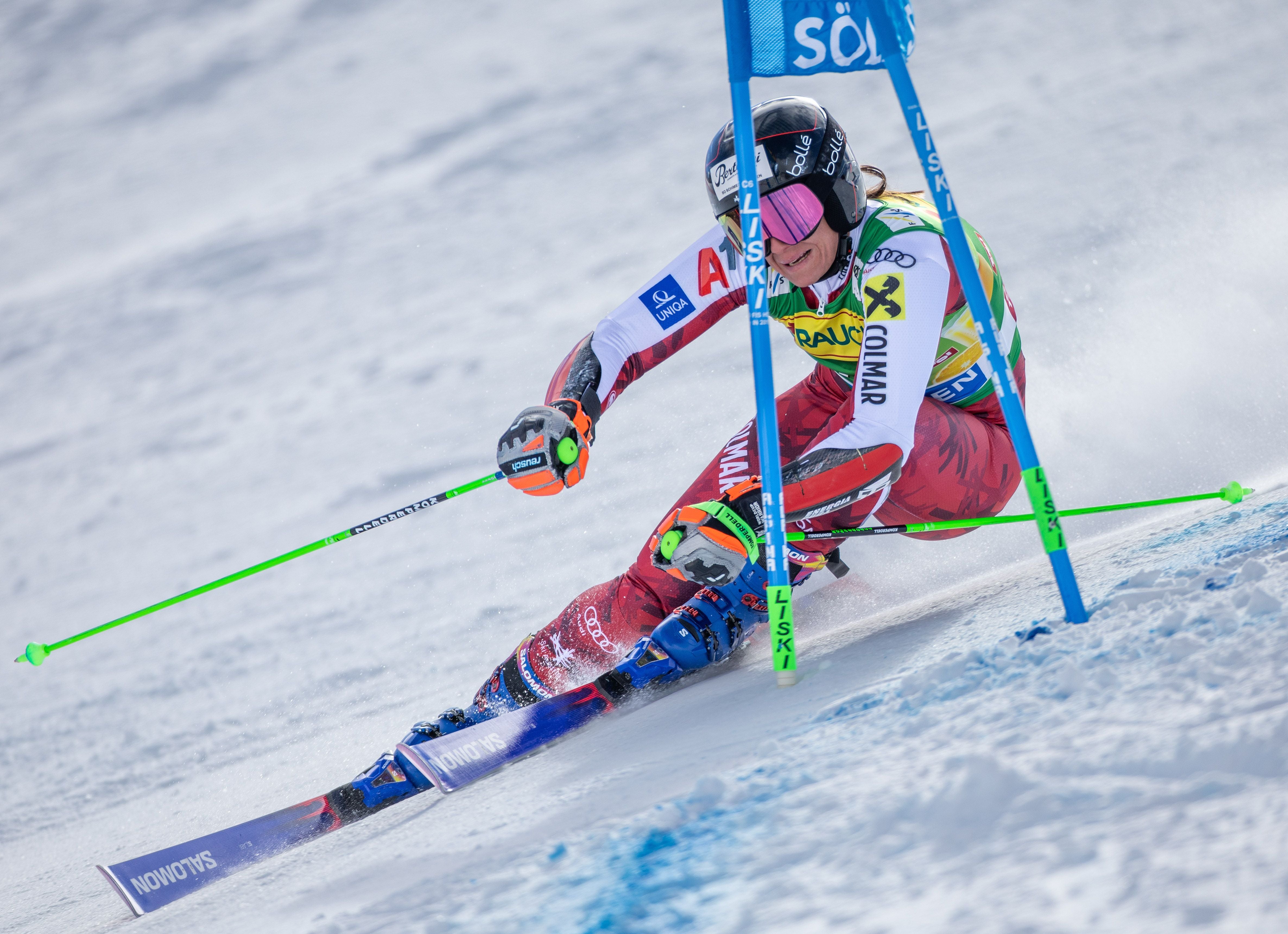 Eine Skirennläuferin fährt beim Riesenslalom um ein blaues Tor im Schnee.