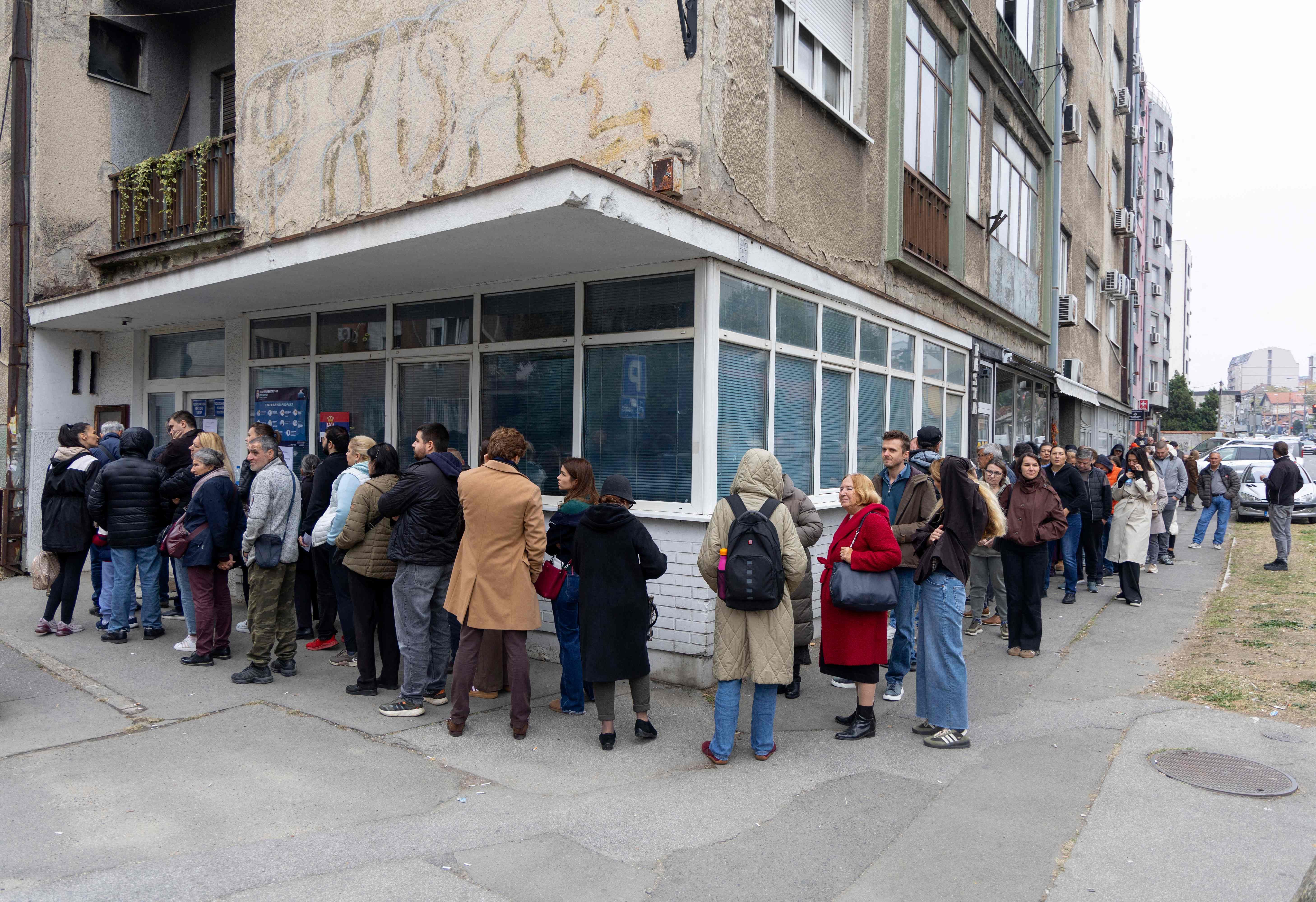 Viele Menschen stehen in einer langen Schlange vor einem Wahllokal in einer Stadt.