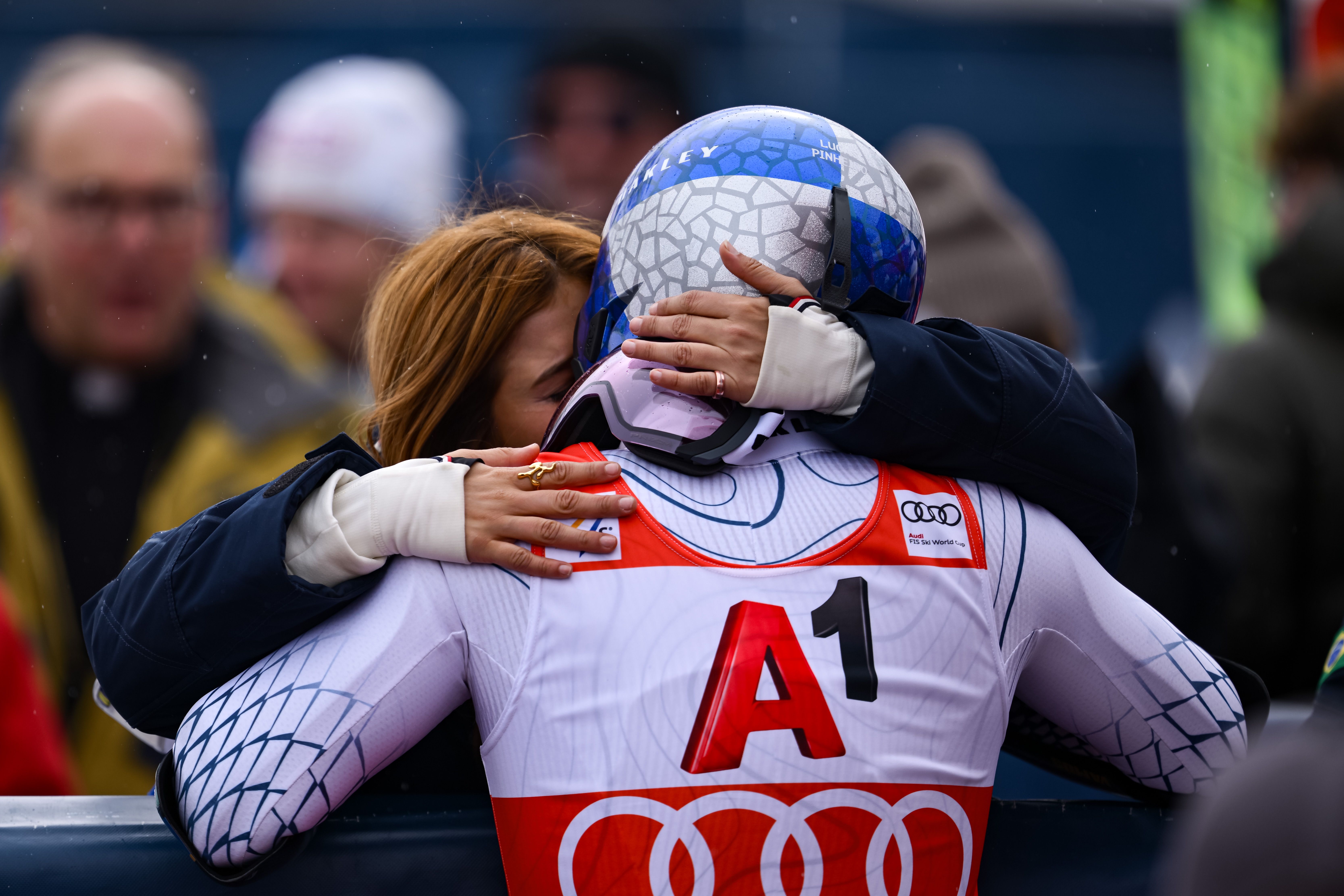 Ein Skifahrer umarmt eine Frau nach einem Skirennen, beide wirken emotional bewegt.