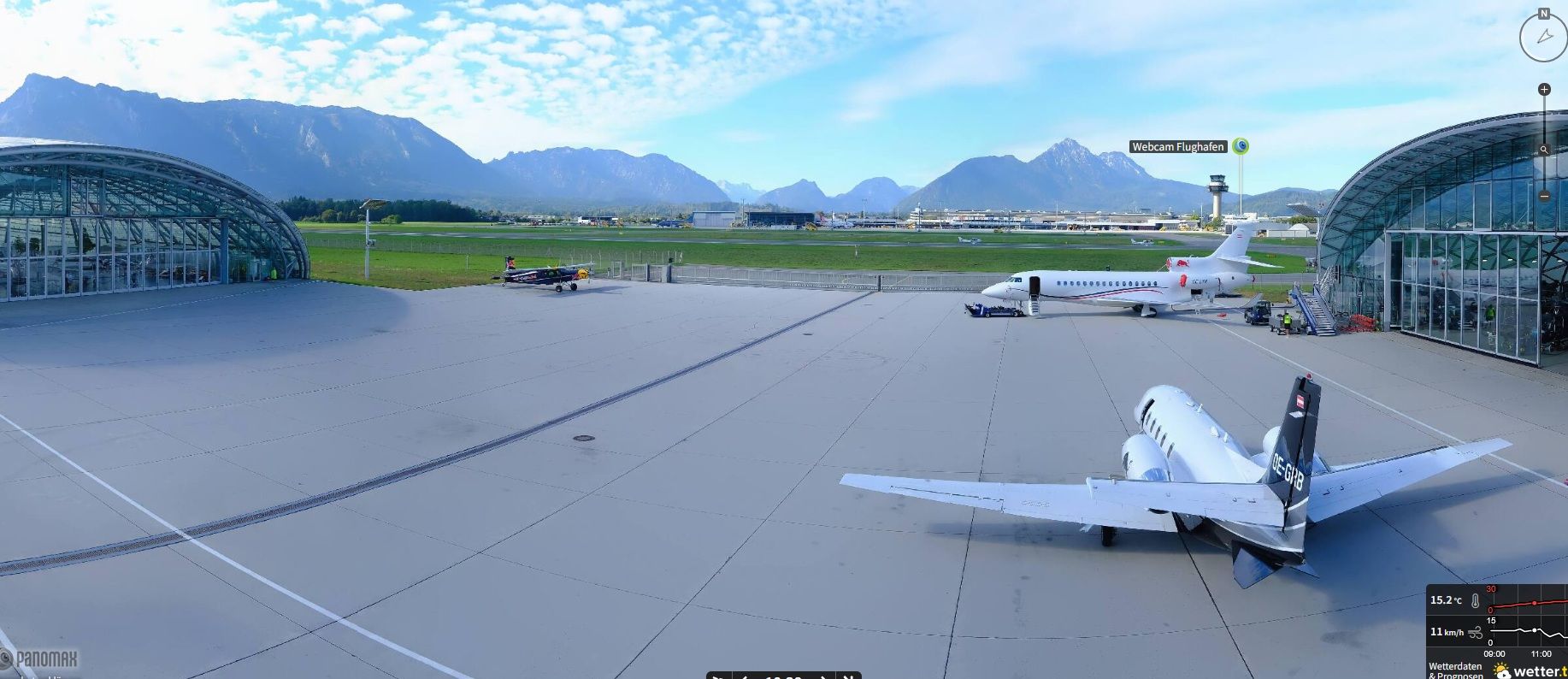 Zwei Flugzeuge stehen auf dem Vorfeld eines Flughafens mit Bergen im Hintergrund.