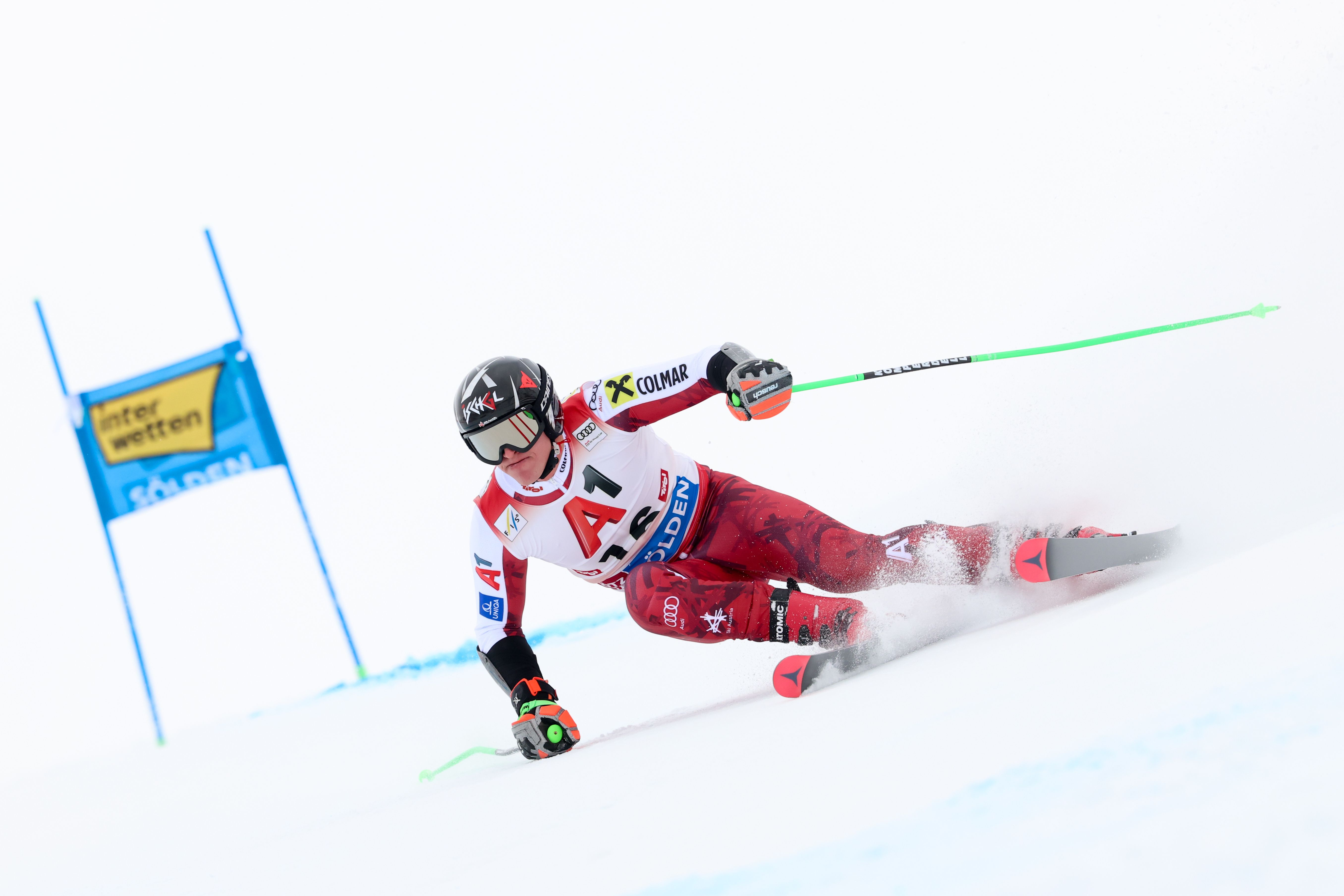 Ein Skirennläufer fährt beim Riesenslalom-Wettbewerb auf einer verschneiten Piste um ein Tor.