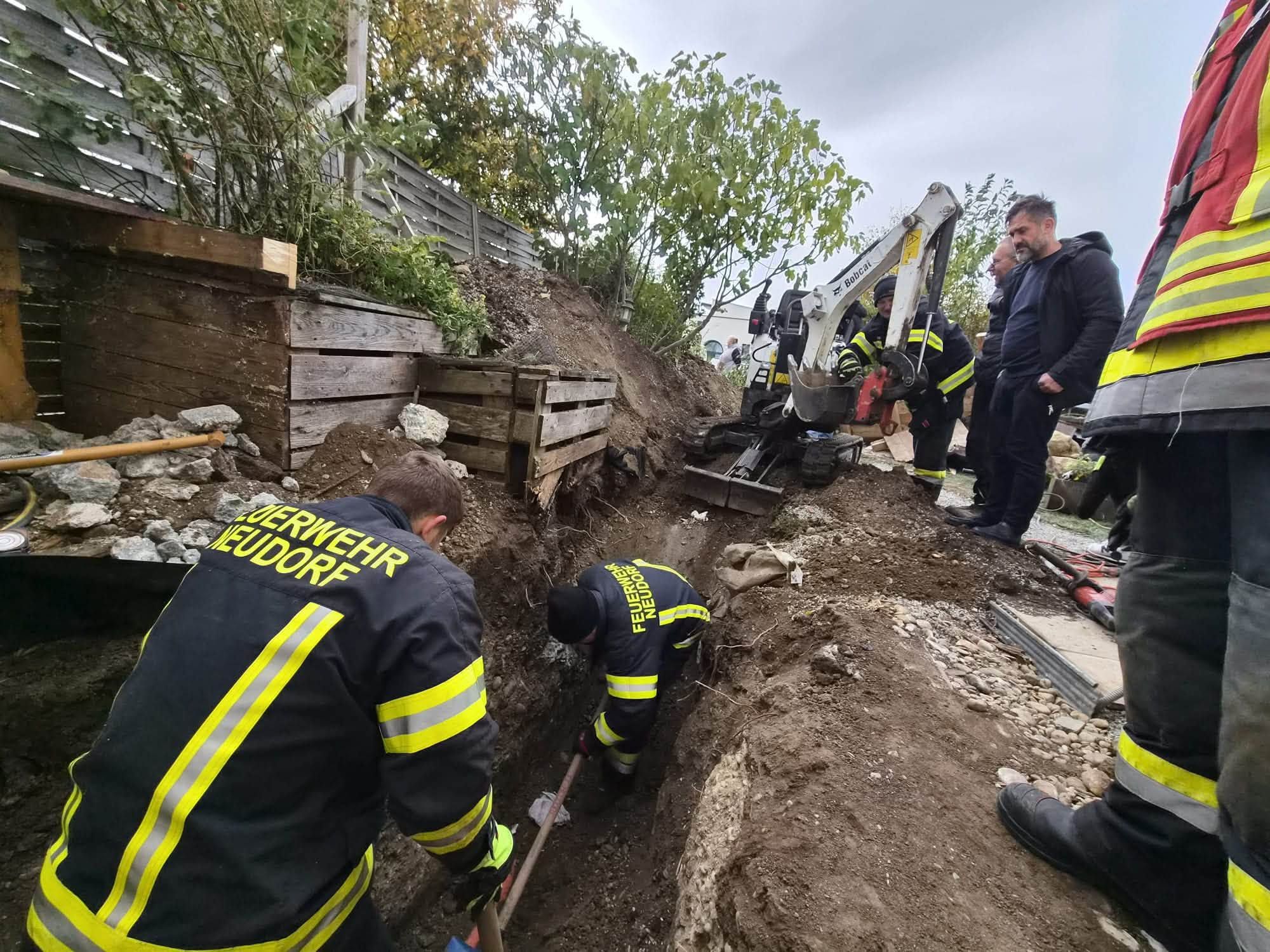 Feuerwehrleute retten eine Katze aus einem Erdloch mit Unterstützung eines Baggers.
