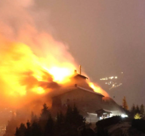 Das Kehlsteinhaus steht am Abend in Flammen, dichter Rauch und helles Feuer sind sichtbar.