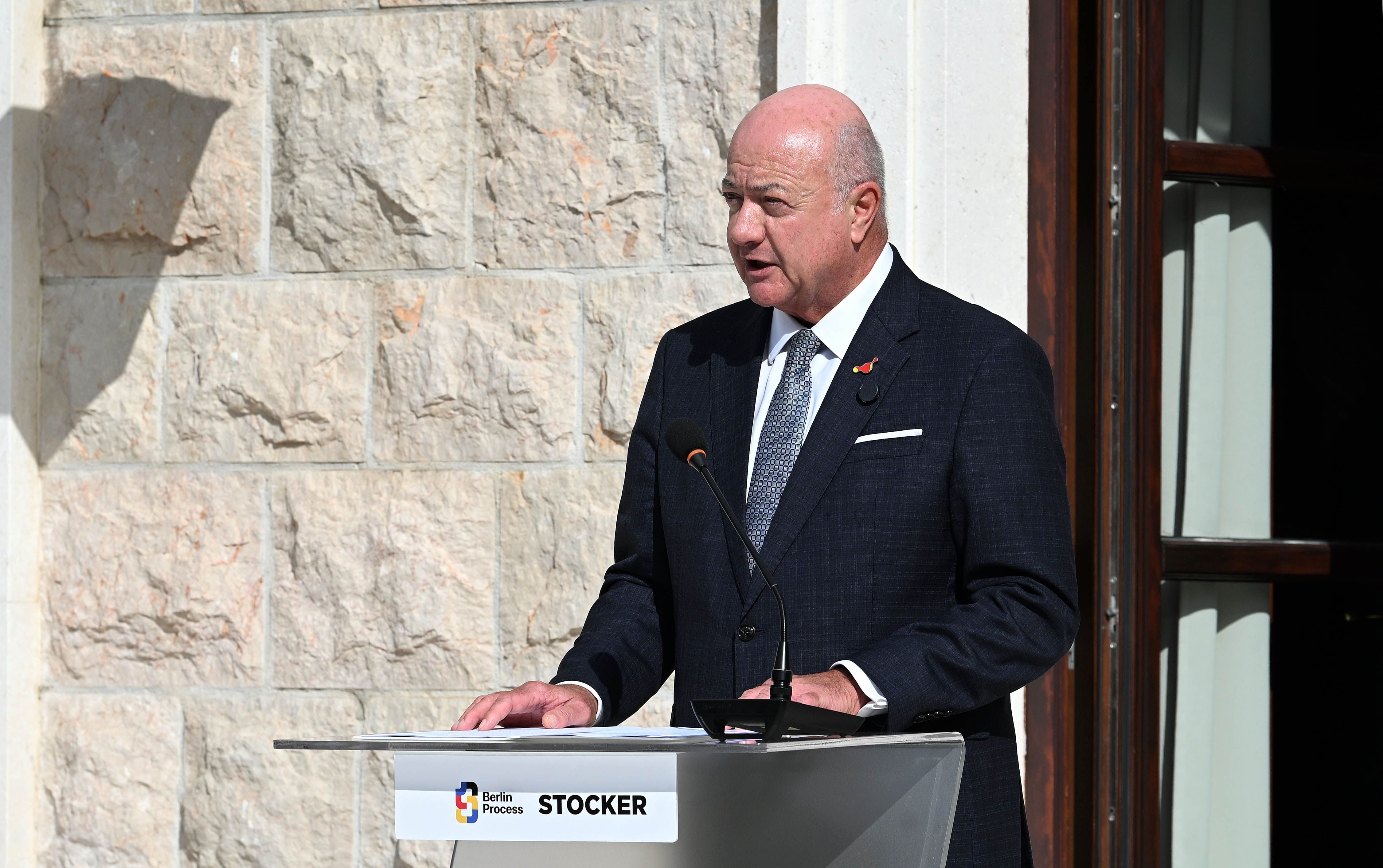 Ein Mann im Anzug spricht bei einer Pressekonferenz im Freien an einem Rednerpult.