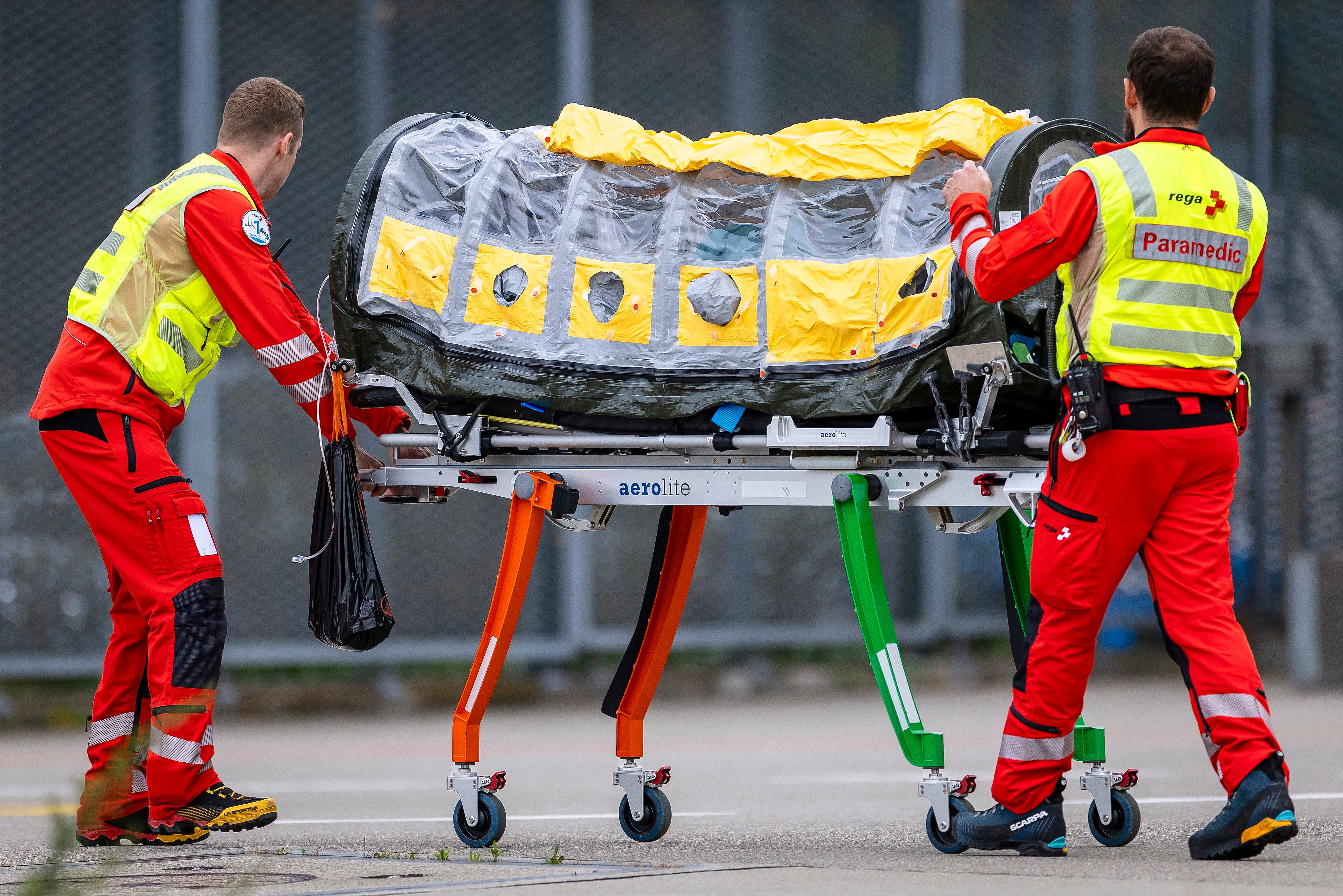 Sanitäter schieben eine isolierte Trage mit einem Patienten am Flughafen Zürich.