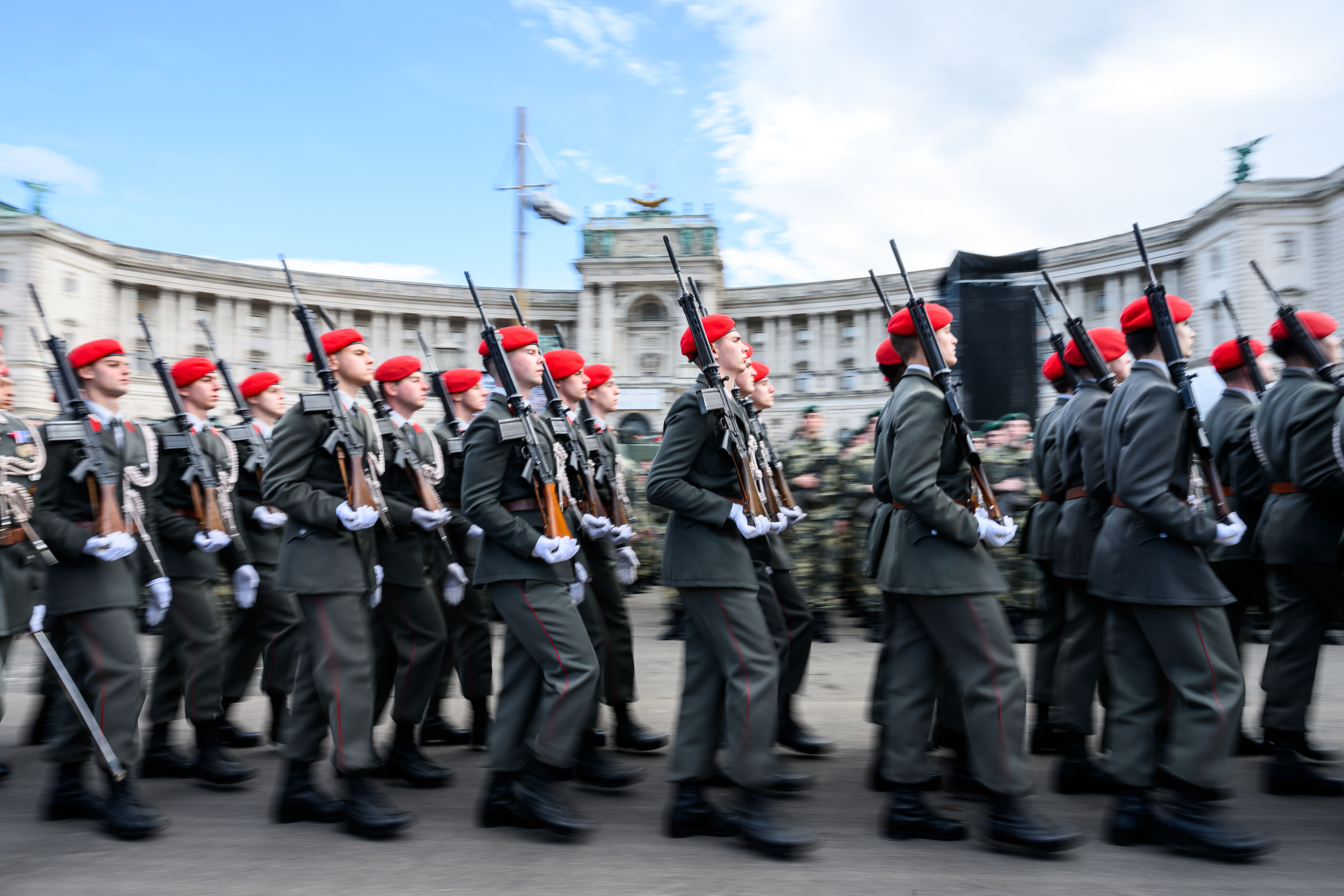 Soldaten mit roten Baretts marschieren am Nationalfeiertag am Heldenplatz in Wien.
