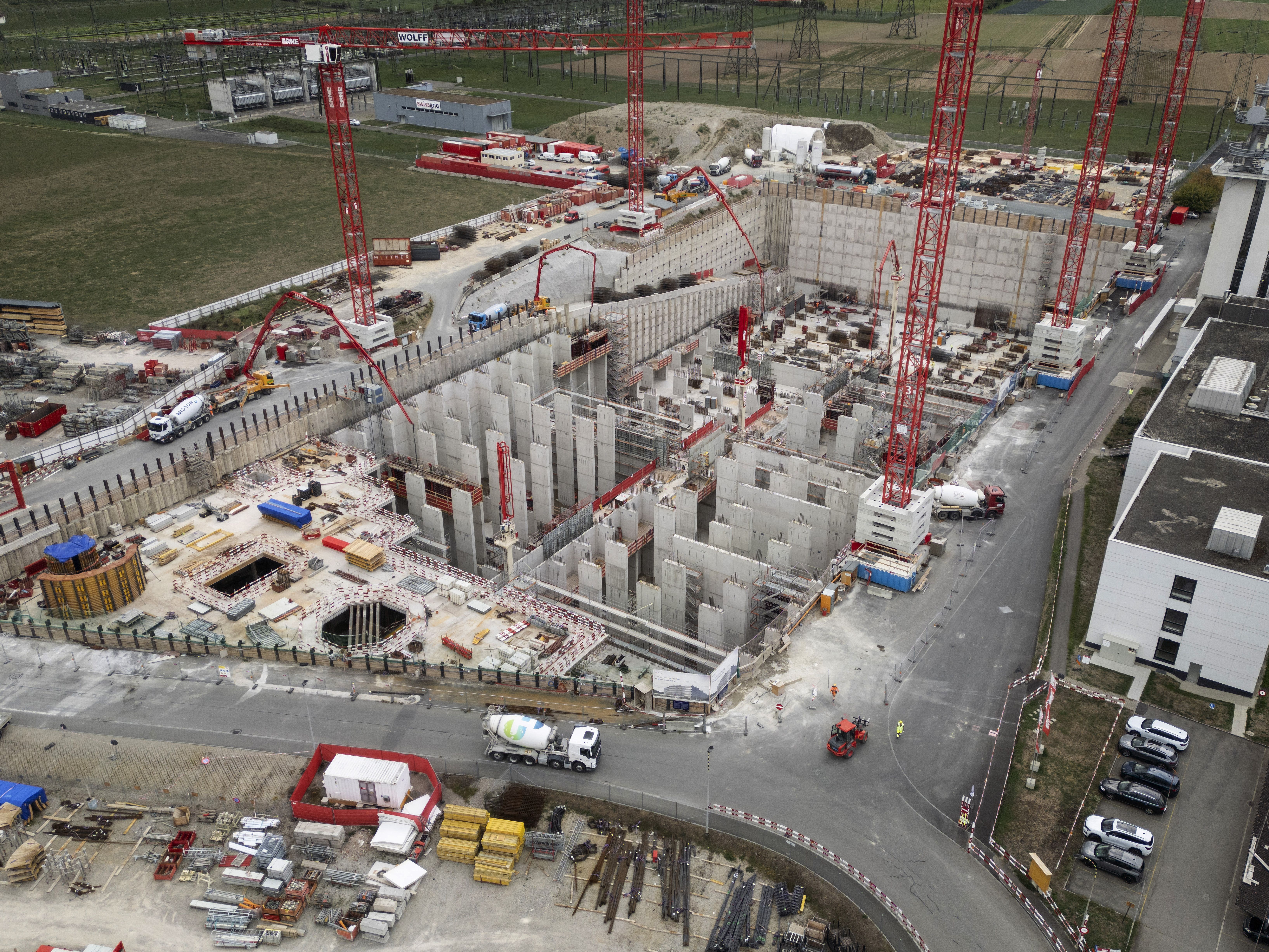 Baustelle eines Technologiezentrums mit Kränen, Betonwänden und Baufahrzeugen, aus der Vogelperspektive.