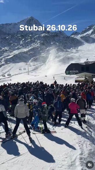 Viele Skifahrer warten am Stubai-Gletscher bei sonnigem Wetter vor einer Seilbahn.